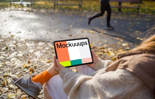 Woman sitting on a bench holding a tablet mockup