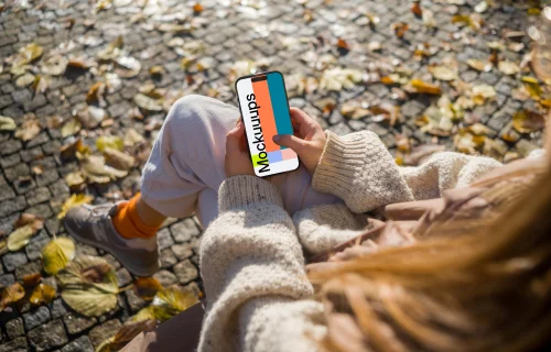 Woman typing on an iPhone 14 Pro in autumn park mockup