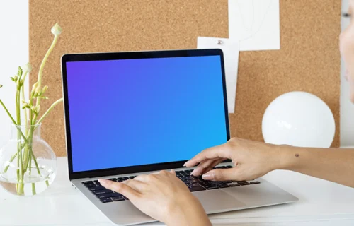 Woman using a MacBook Pro mockup in front of a bulletin board
