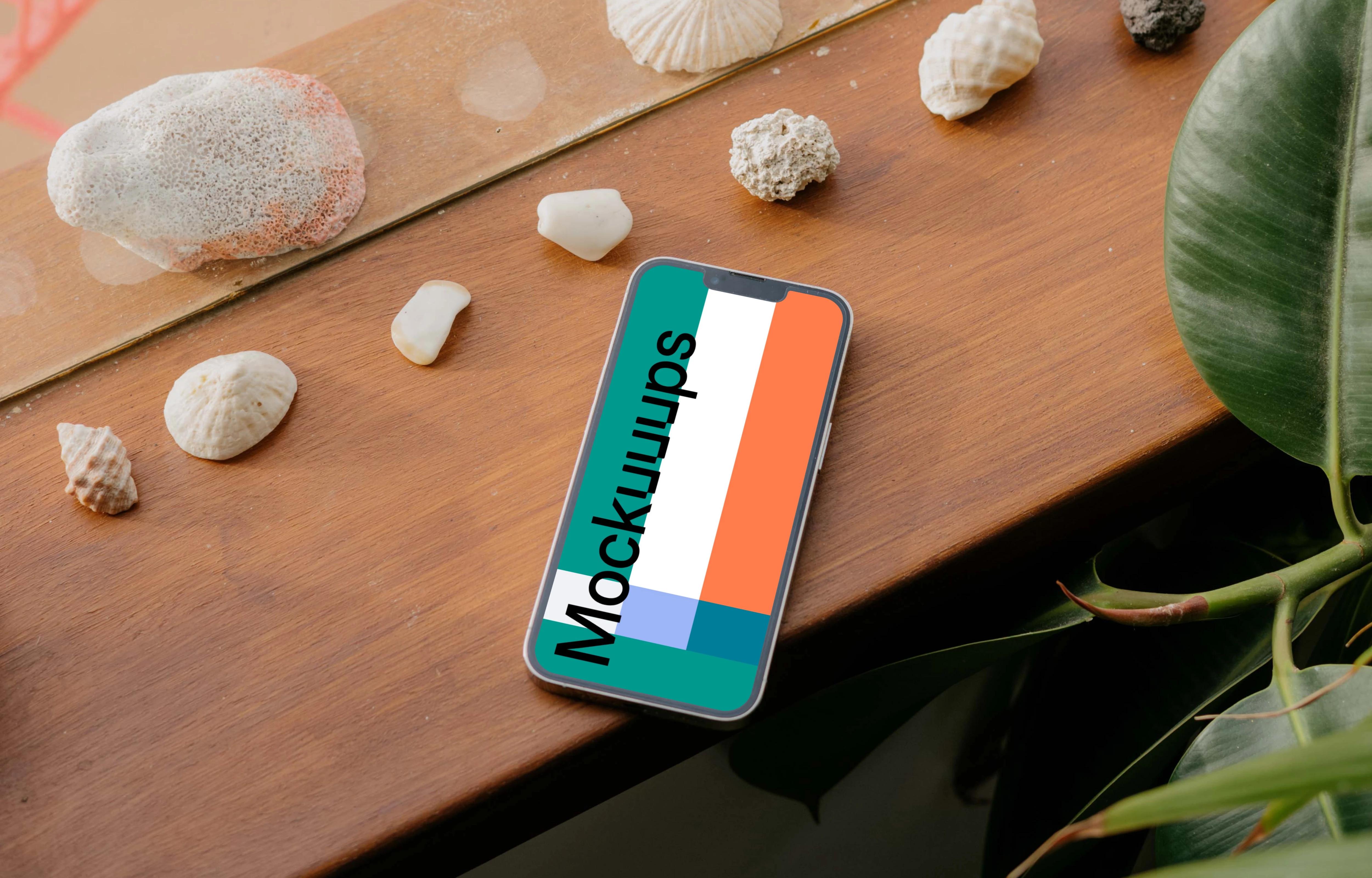 iPhone 13 Pro mockup on a wooden table next to seashells