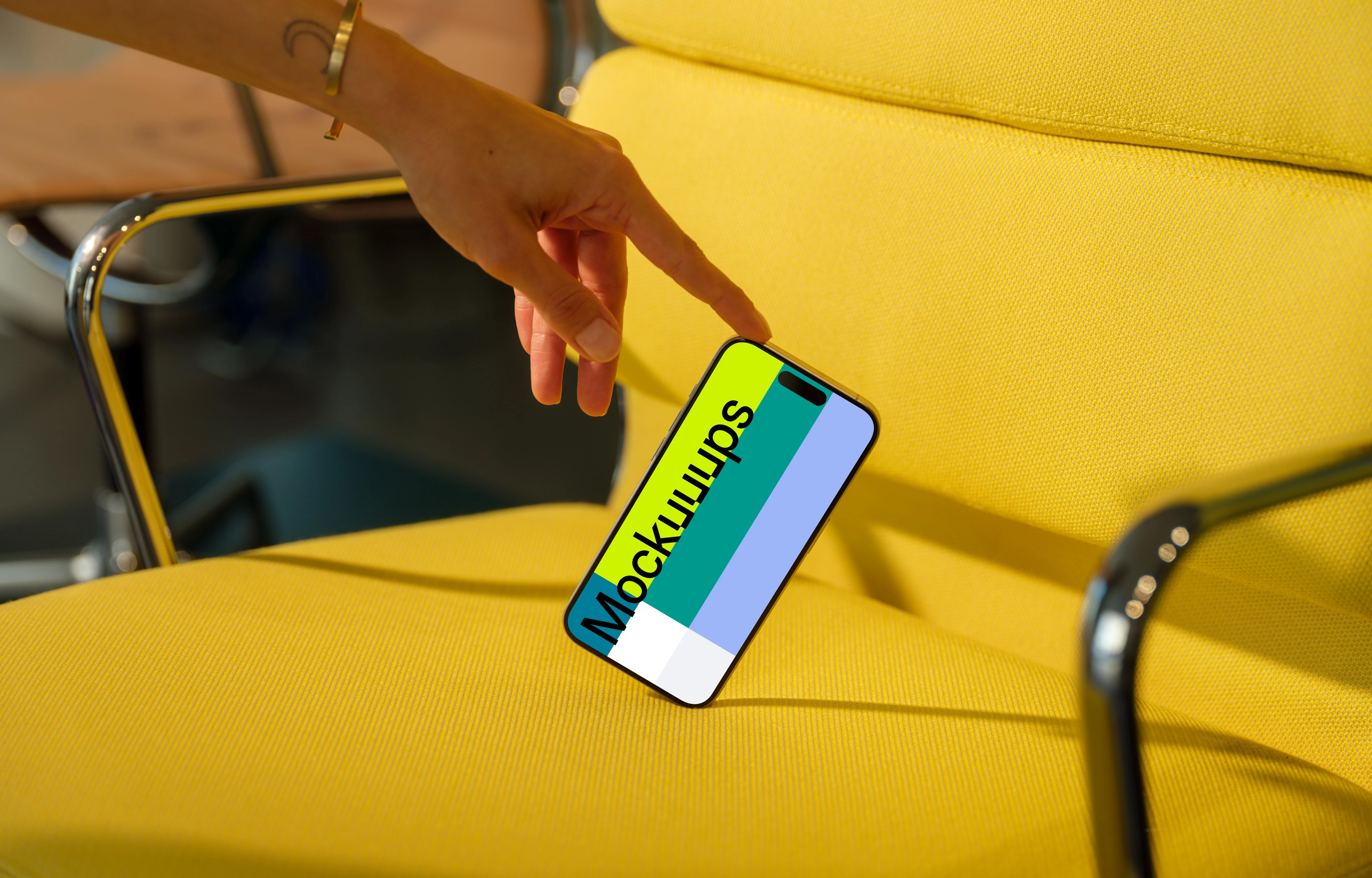 iPhone 15 Pro mockup with hand interaction on yellow chair
