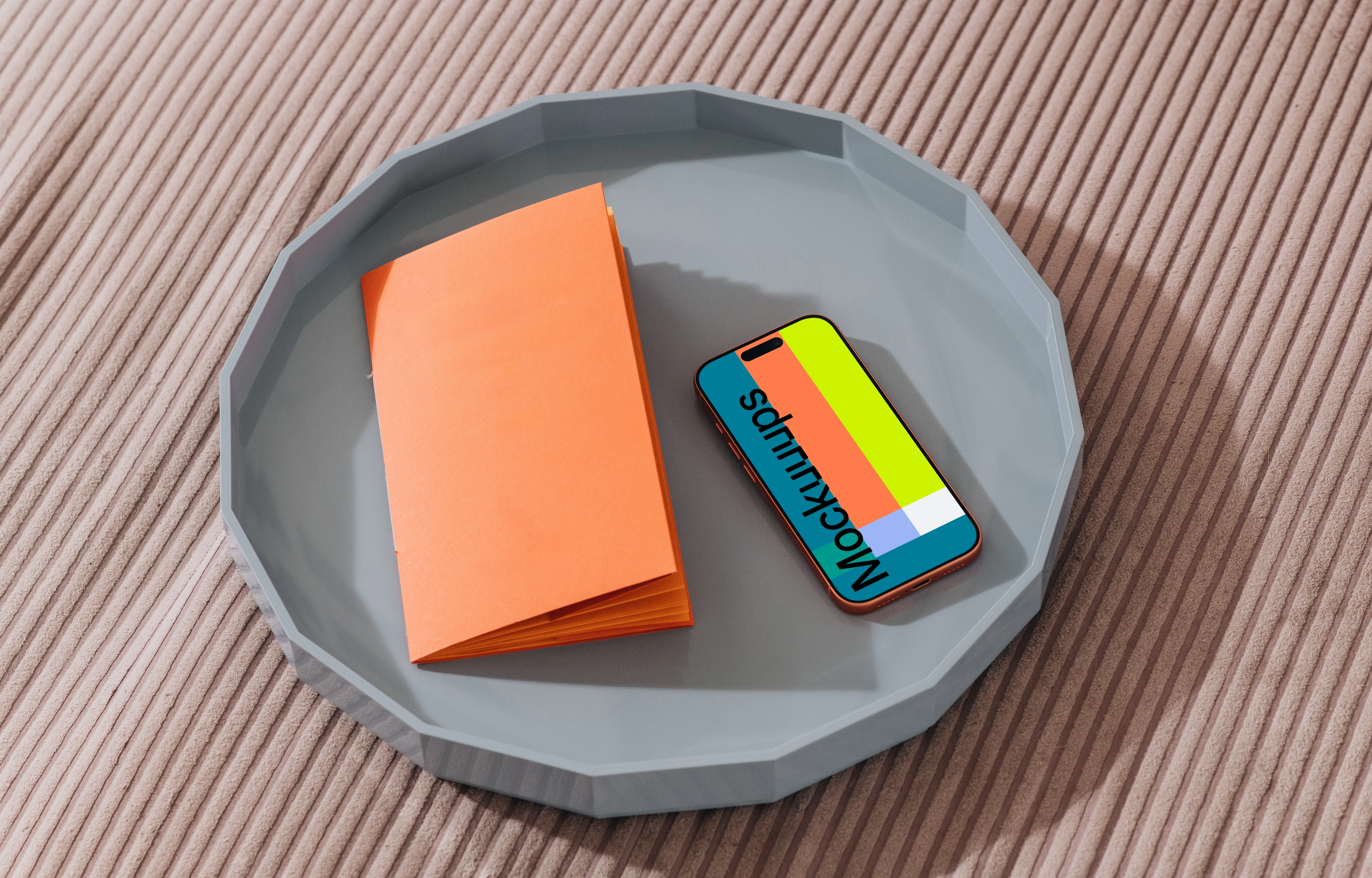 iPhone 17 Pro mockup on a gray tray with an orange notebook