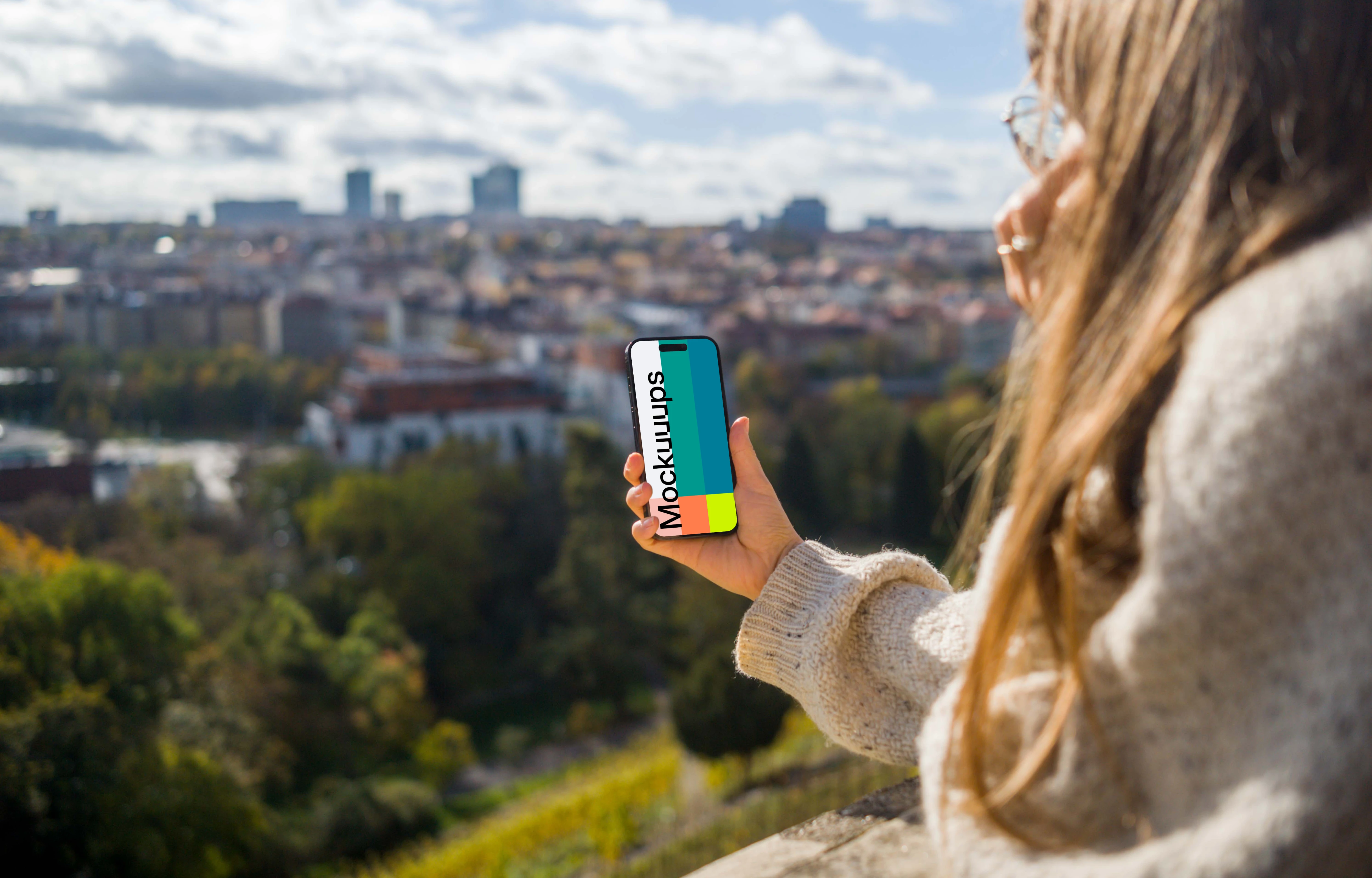 Woman hand holding an iPhone with city view mockup