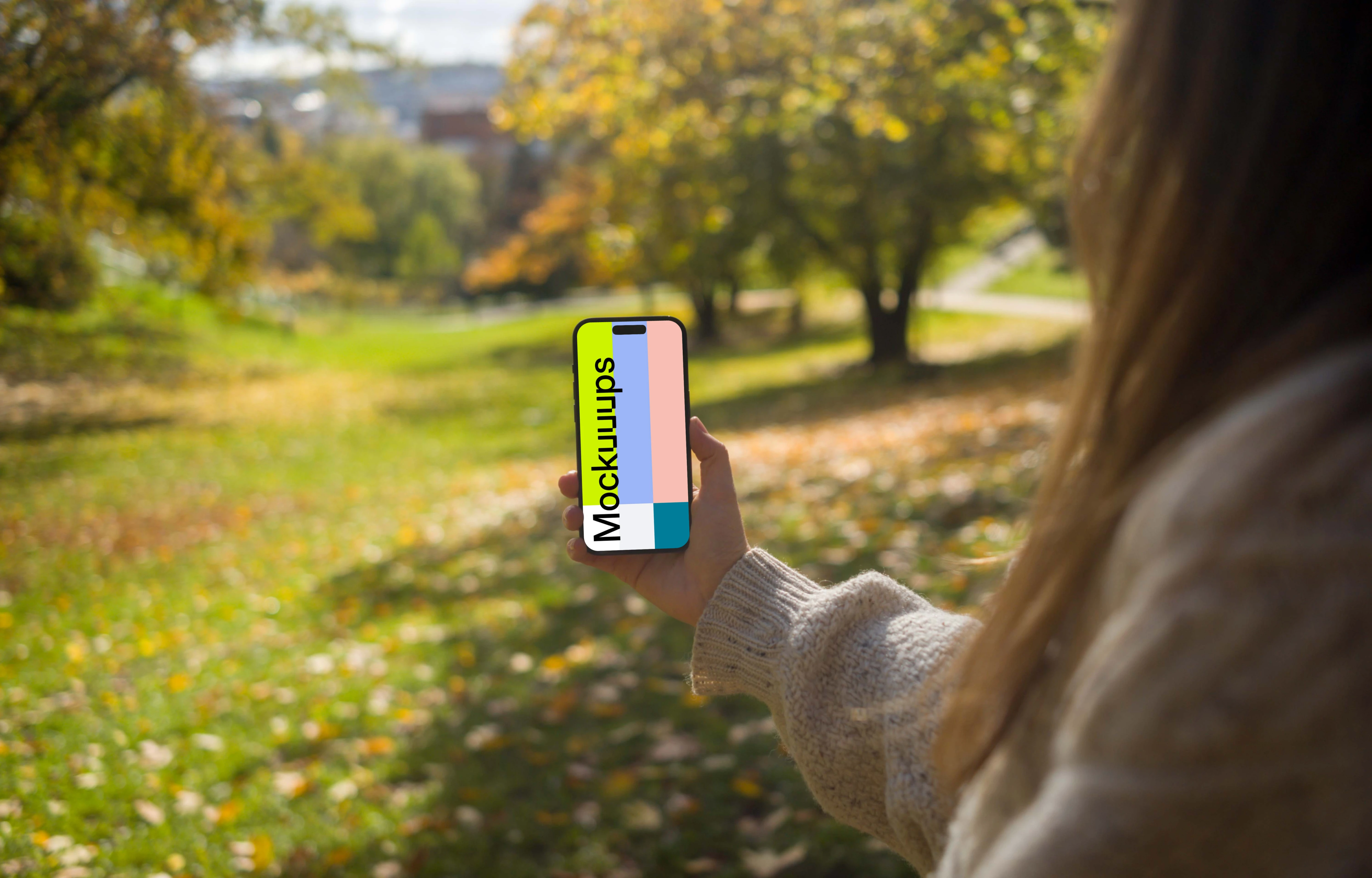 Woman holding an iPhone 14 Pro in nature mockup