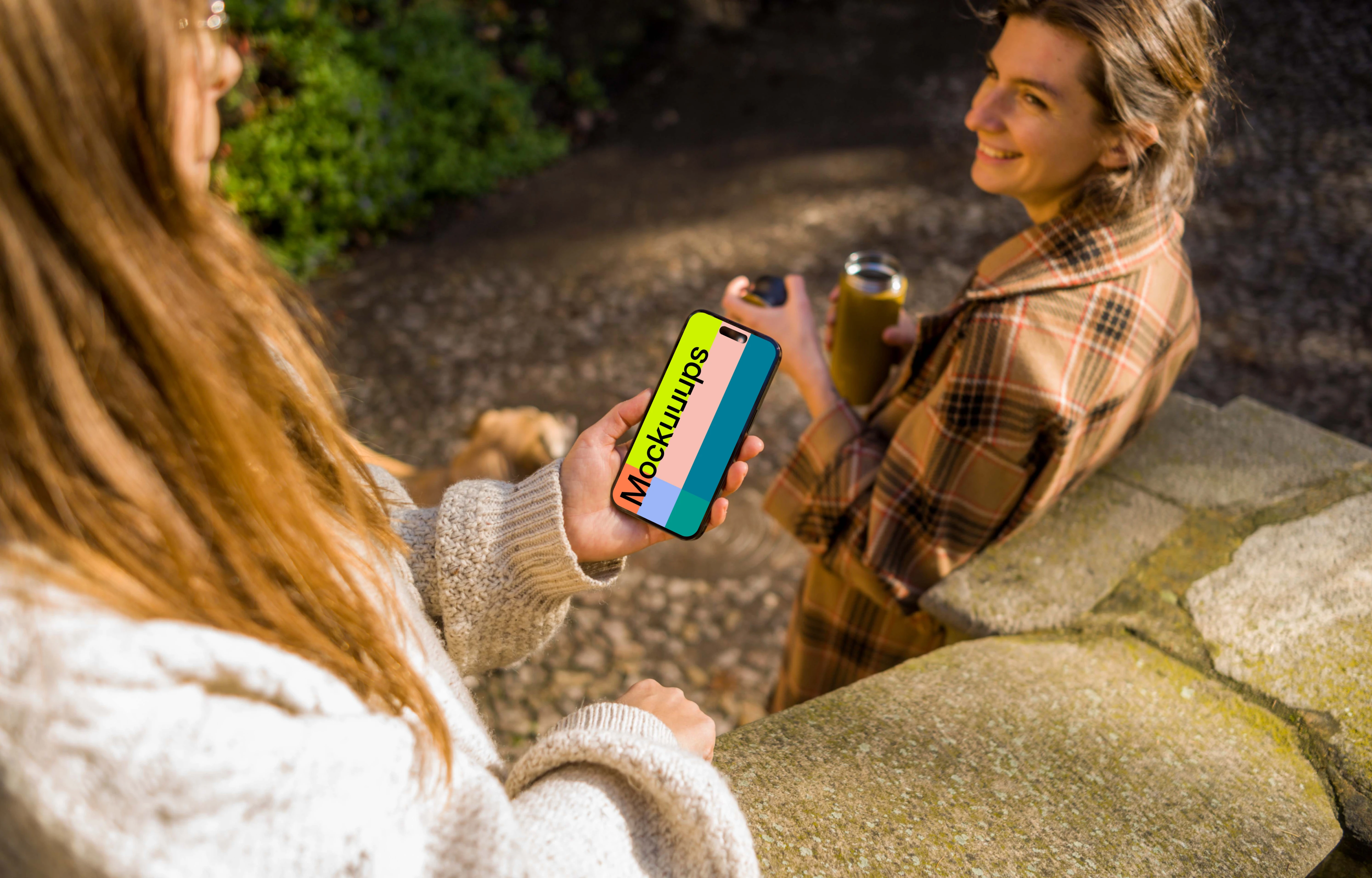 Woman holding an iPhone 14 Pro next to the friend mockup