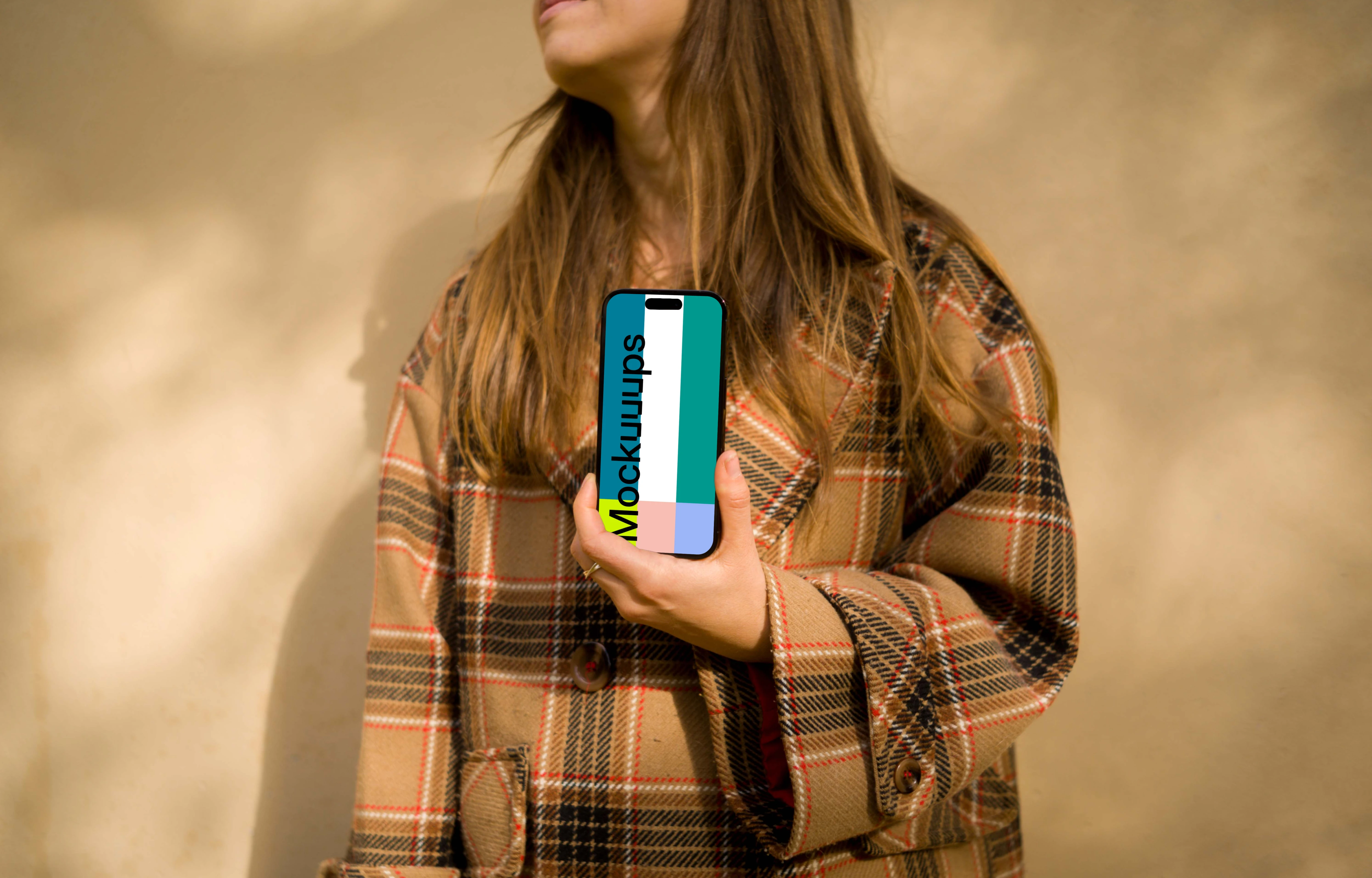 Woman in coat holding an iPhone 14 Pro mockup