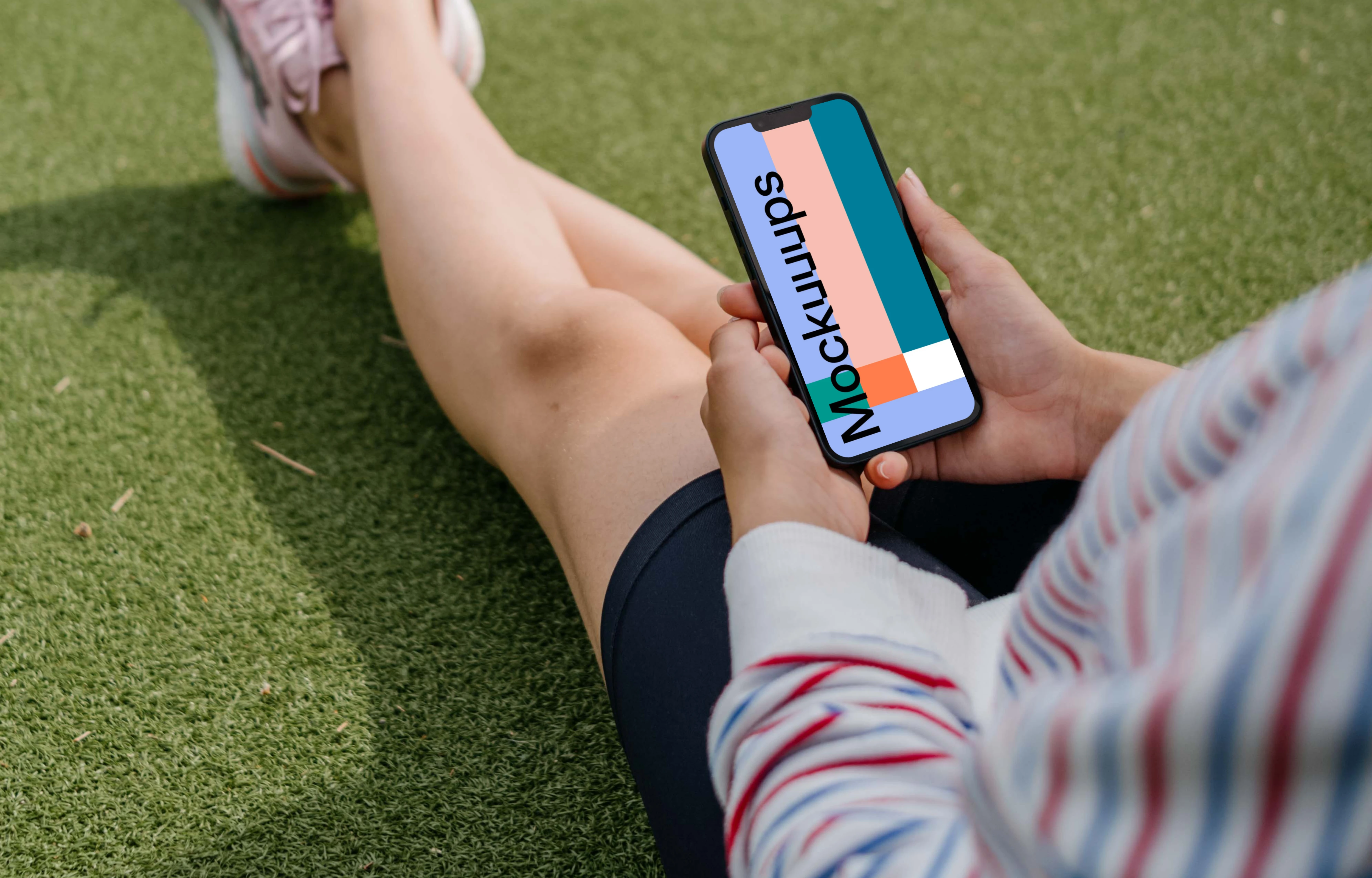 Young woman holding a smartphone mockup on a grass