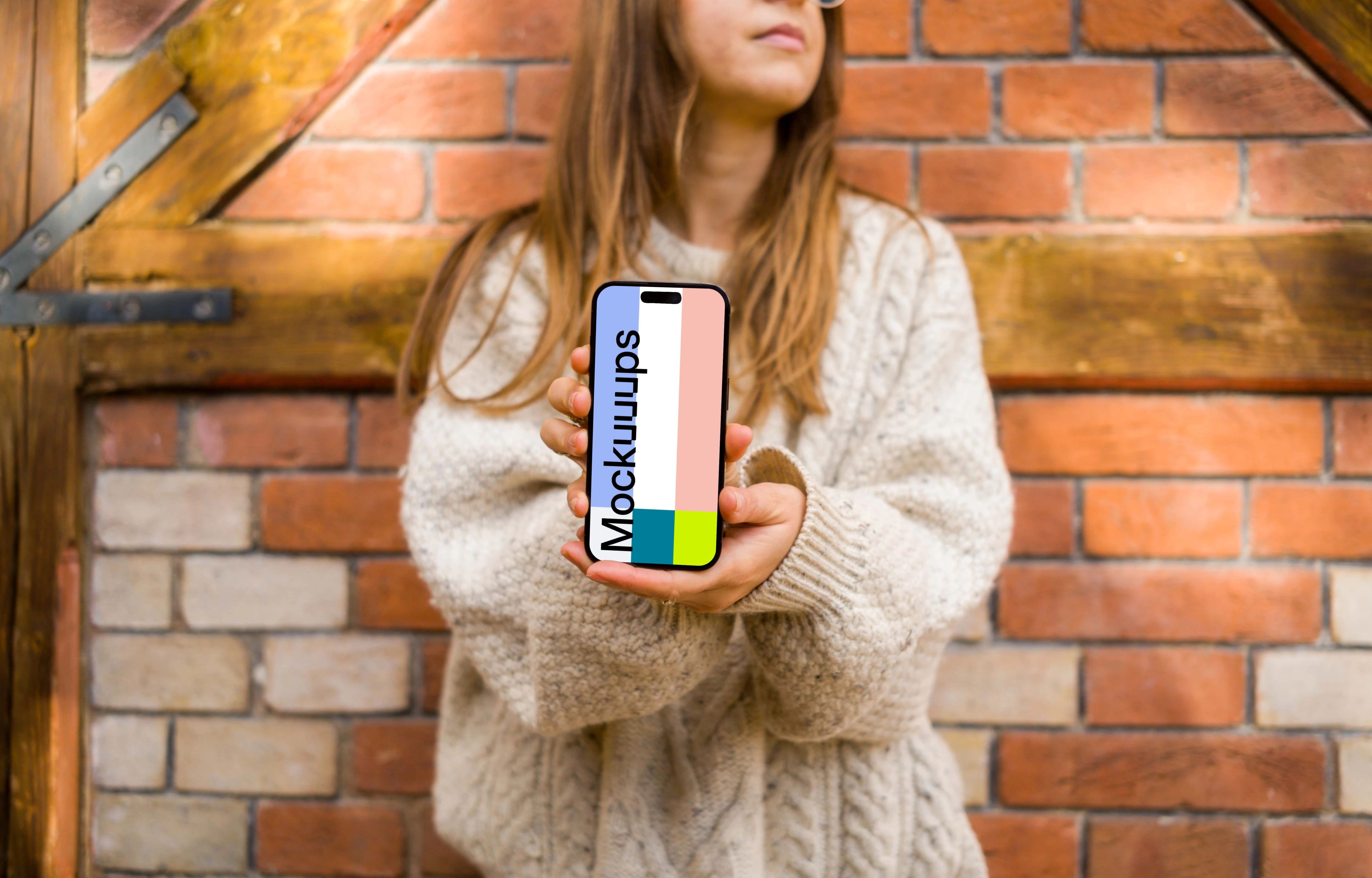 Woman in sweater holding an iPhone 14 Pro mockup
