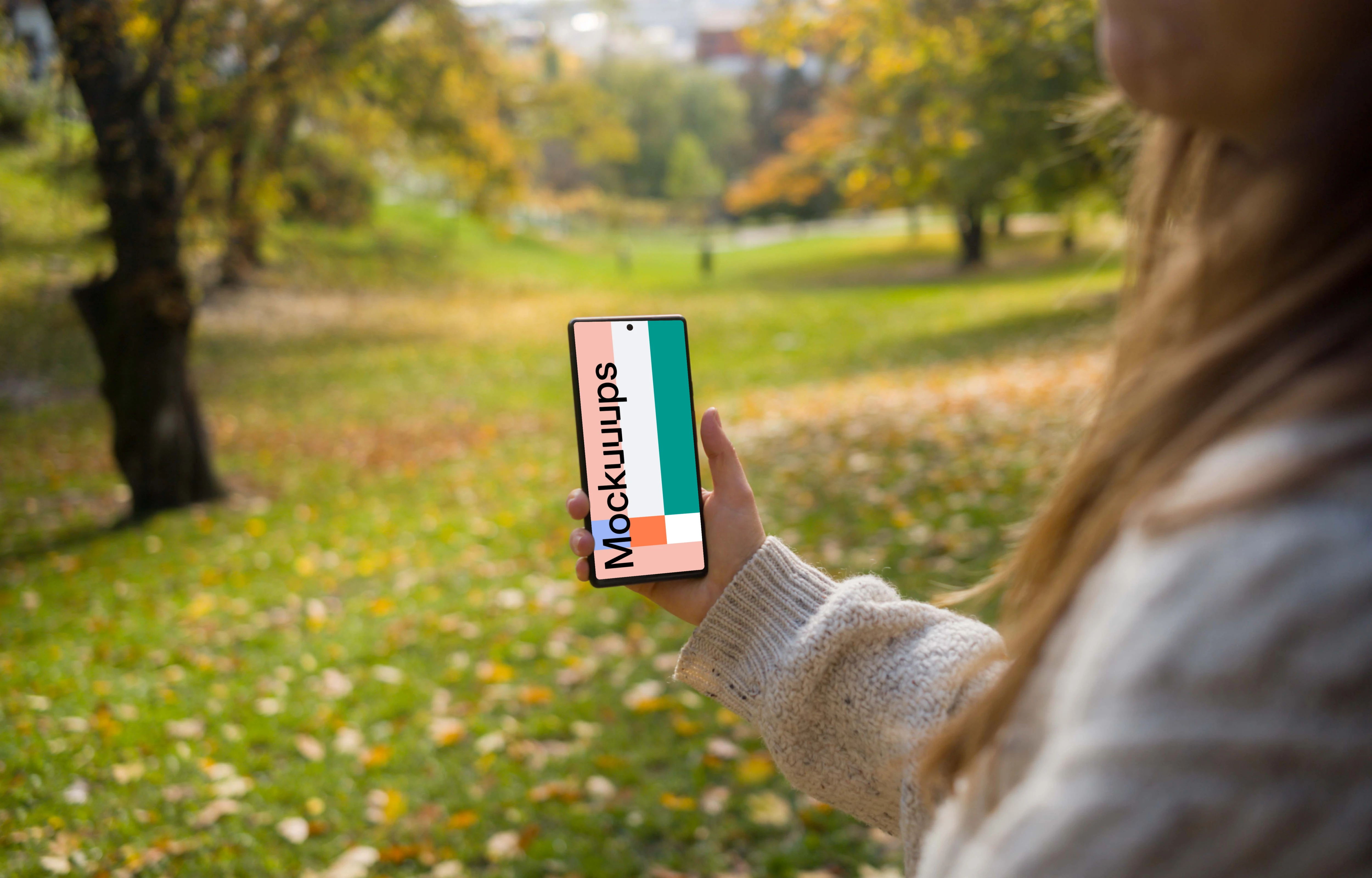 Woman hand holding a phone mockup in the autumn season