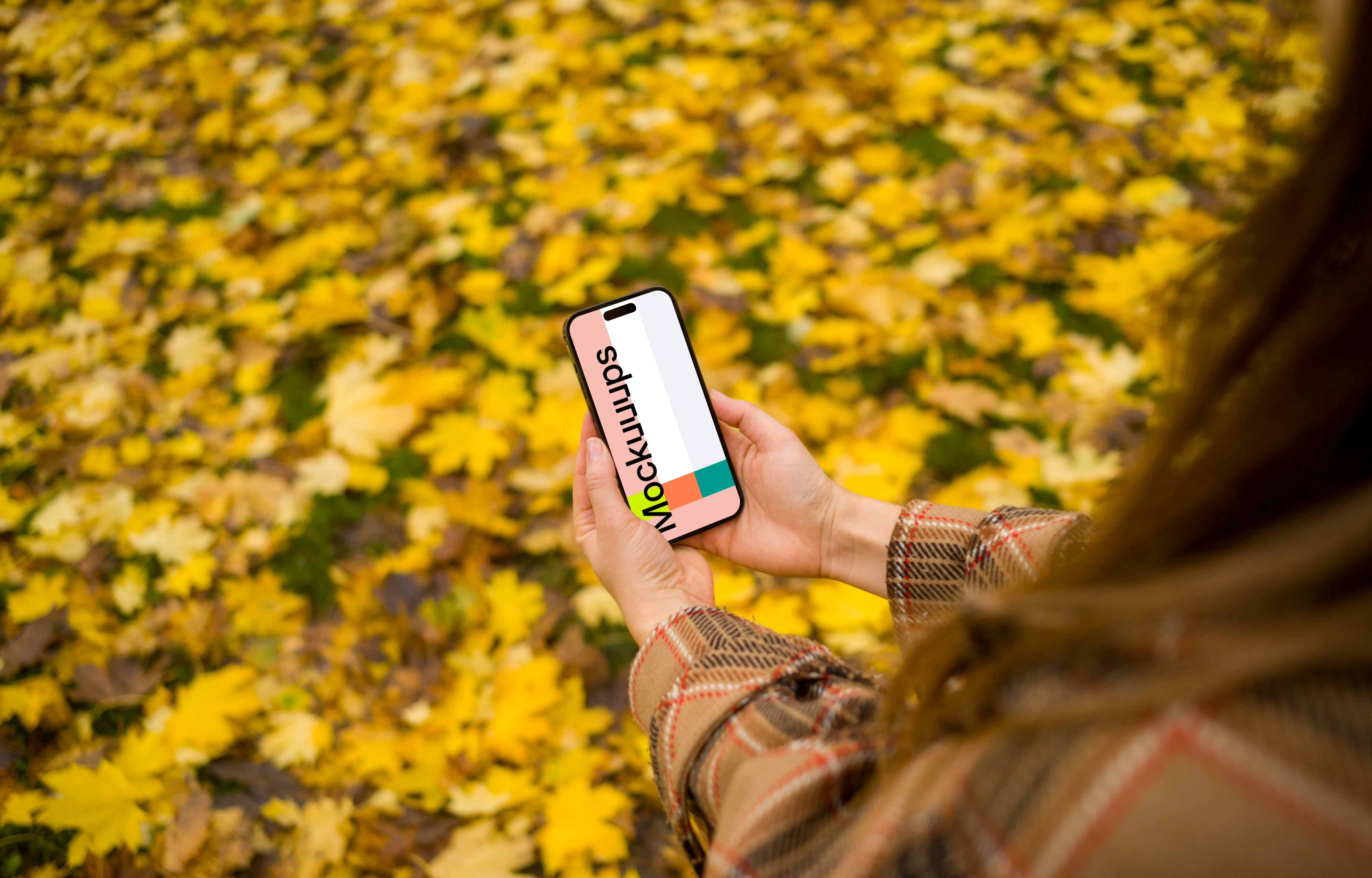 Woman hands holding an iPhone 14 Pro in autumn theme mockup
