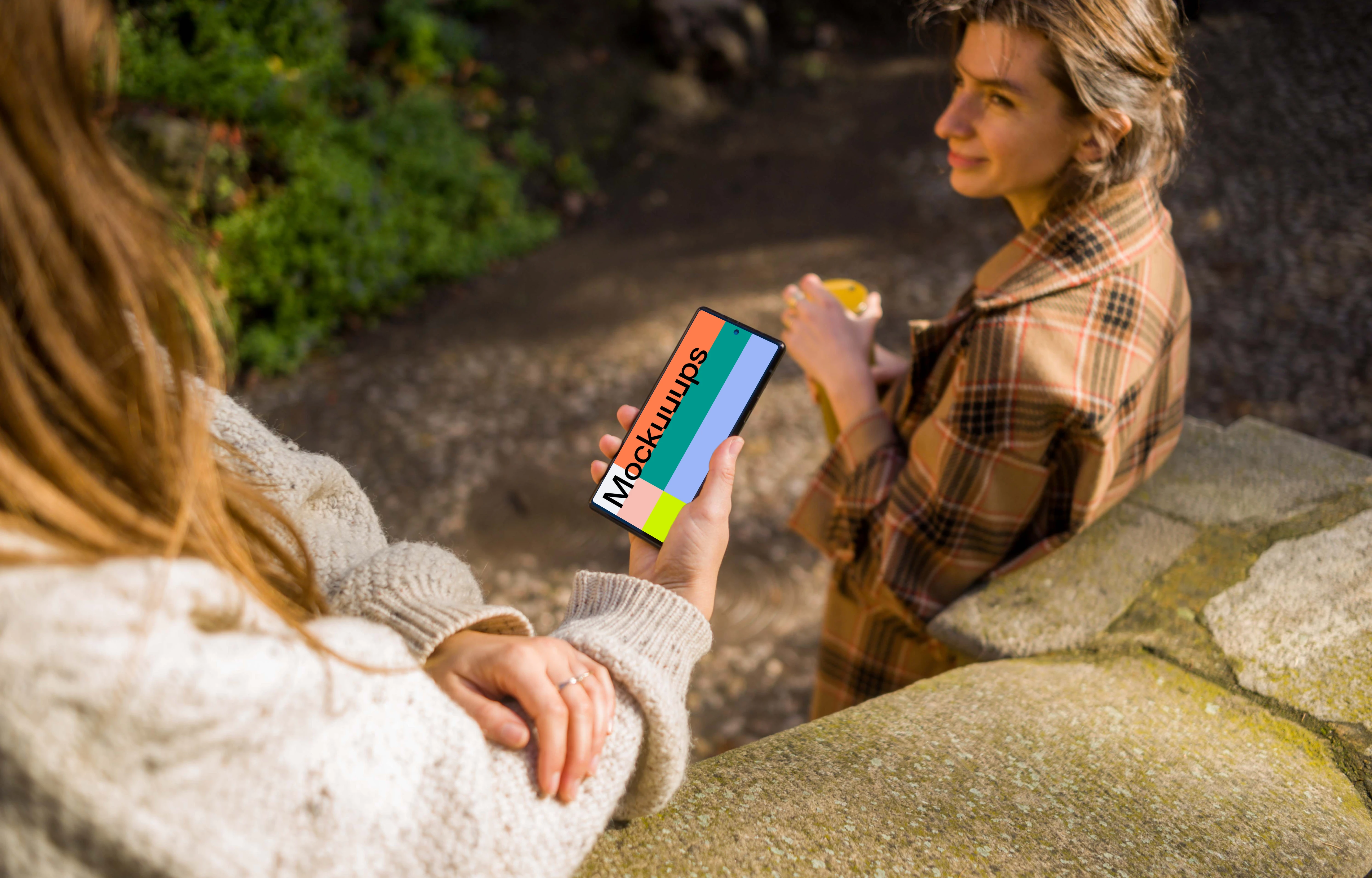 Woman holding a Google Pixel 6 next to a friend mockup