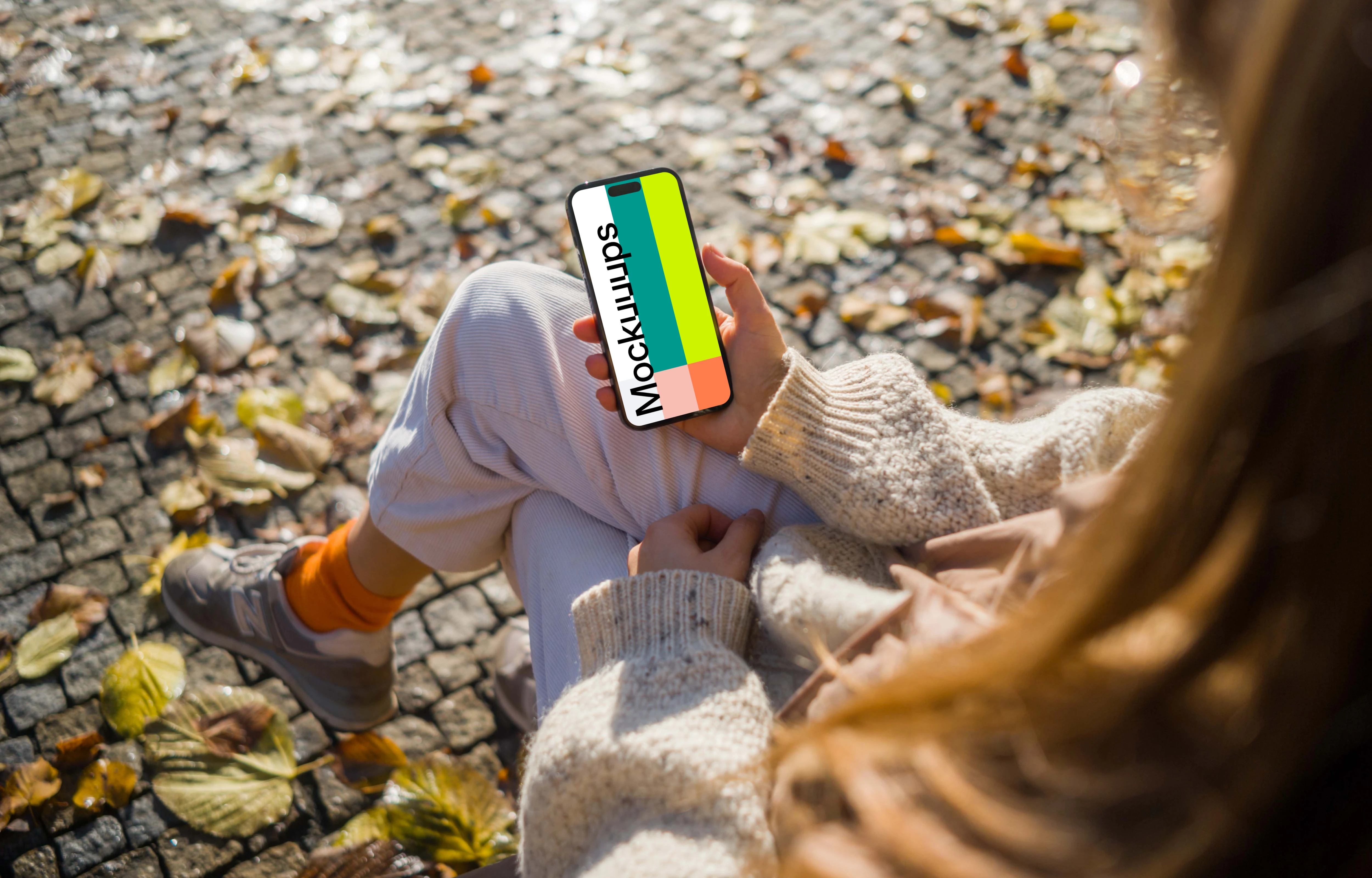Woman holding an iPhone in autumn theme mockup