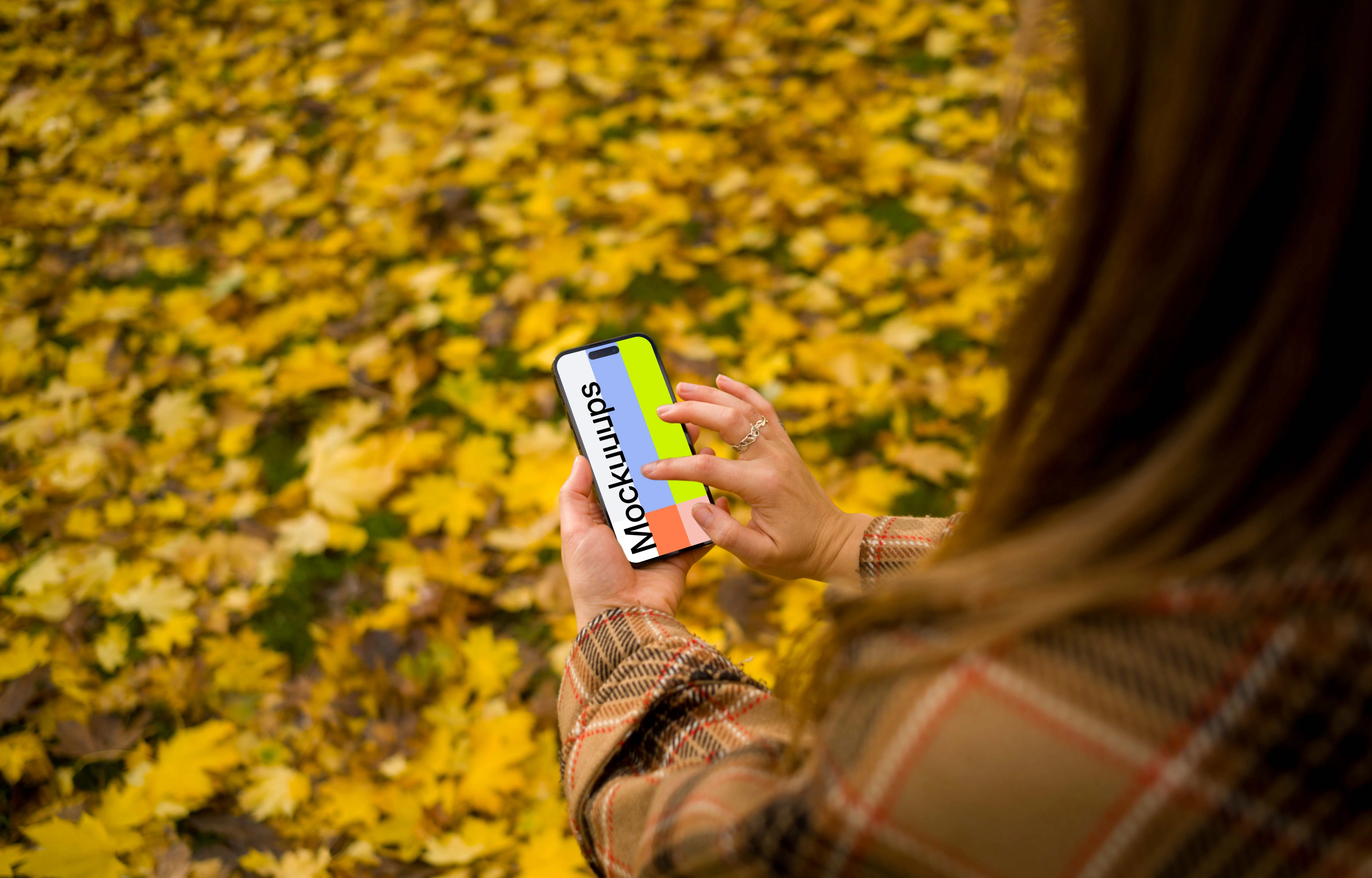 Woman typing on an iPhone 14 Pro in autumn theme mockup