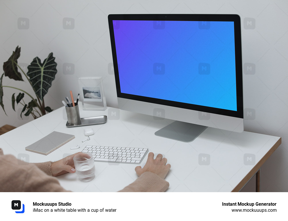 iMac on a white table with a cup of water