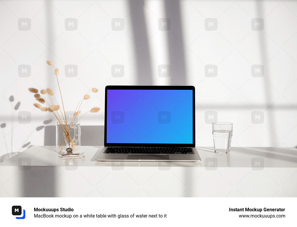 MacBook mockup on a white table with glass of water next to it