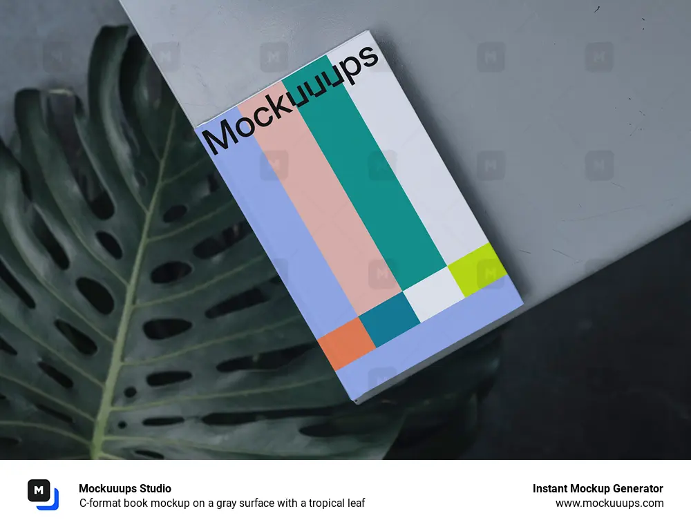 C-format book mockup on a gray surface with a tropical leaf