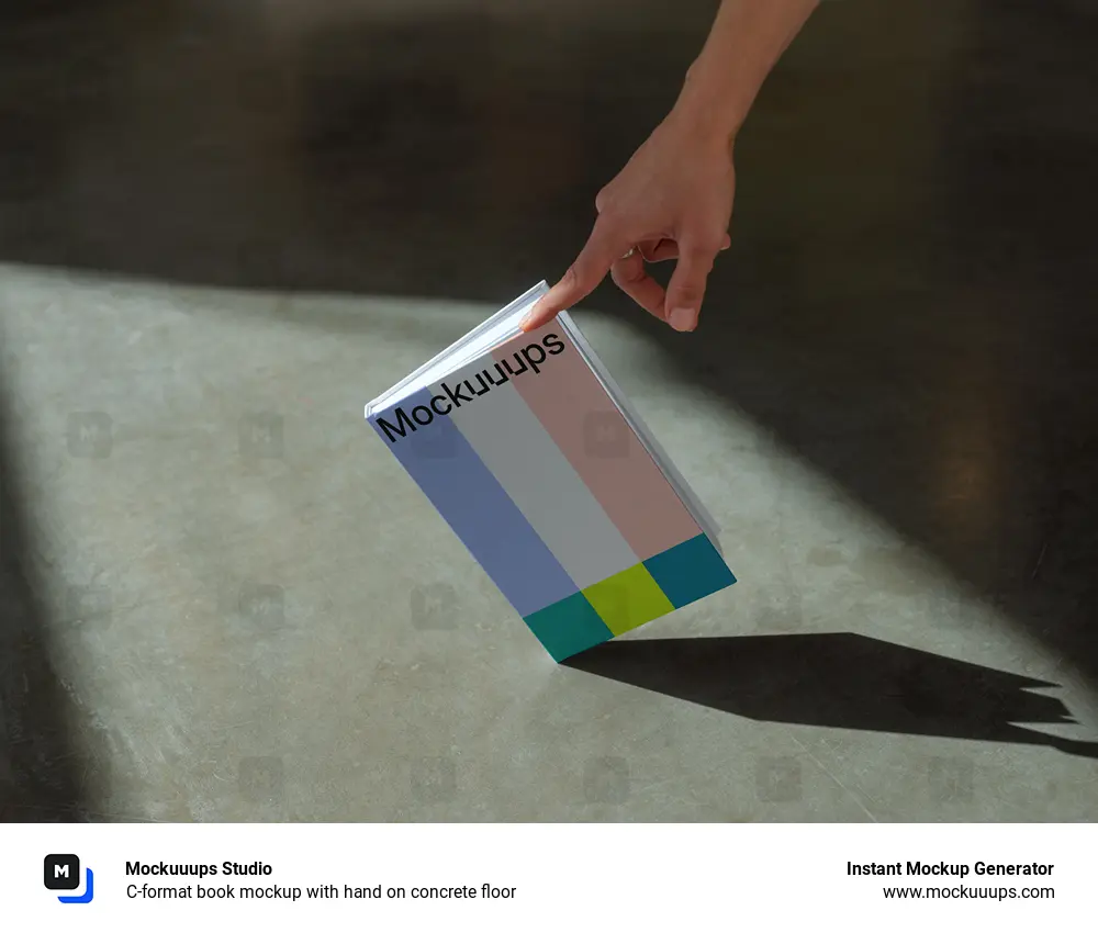 C-format book mockup with hand on concrete floor
