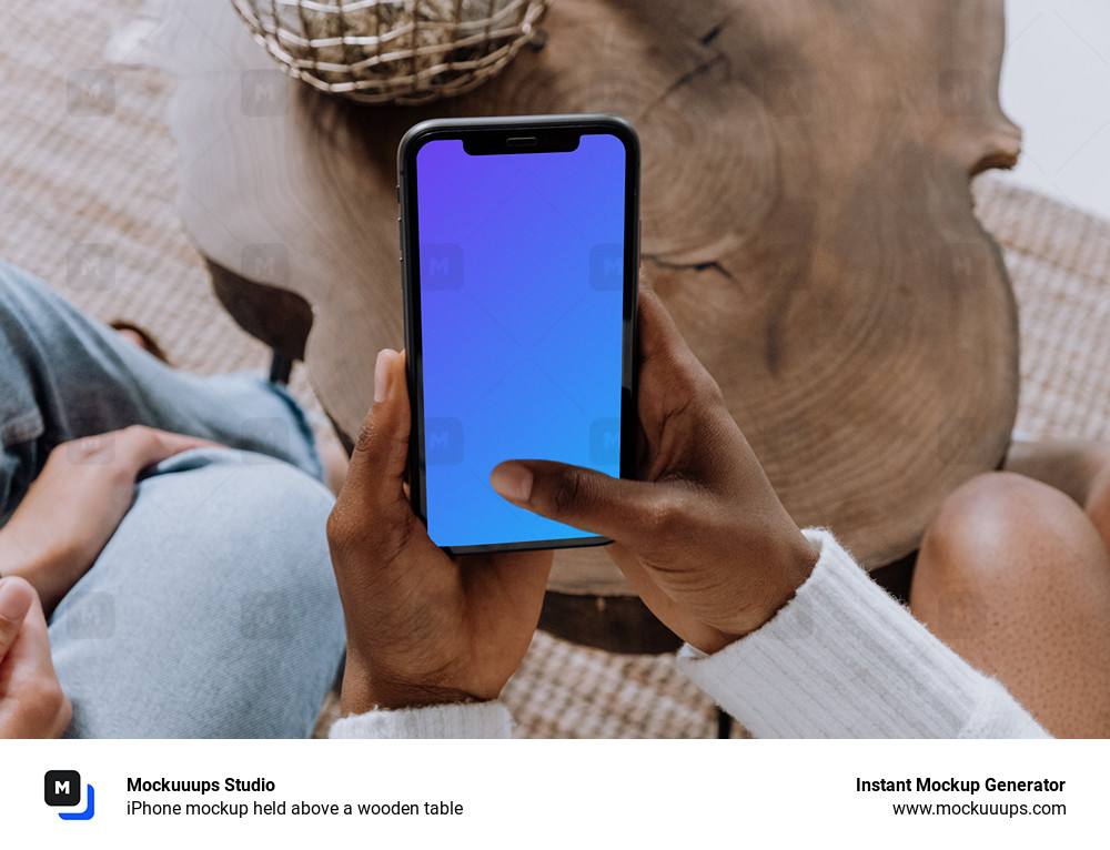 iPhone mockup held above a wooden table