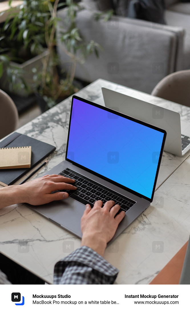 MacBook Pro mockup on a white table beside a notebook