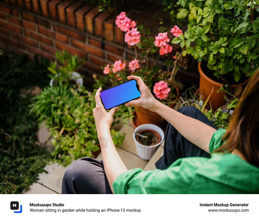 Woman sitting in garden while holding an iPhone 13 mockup
