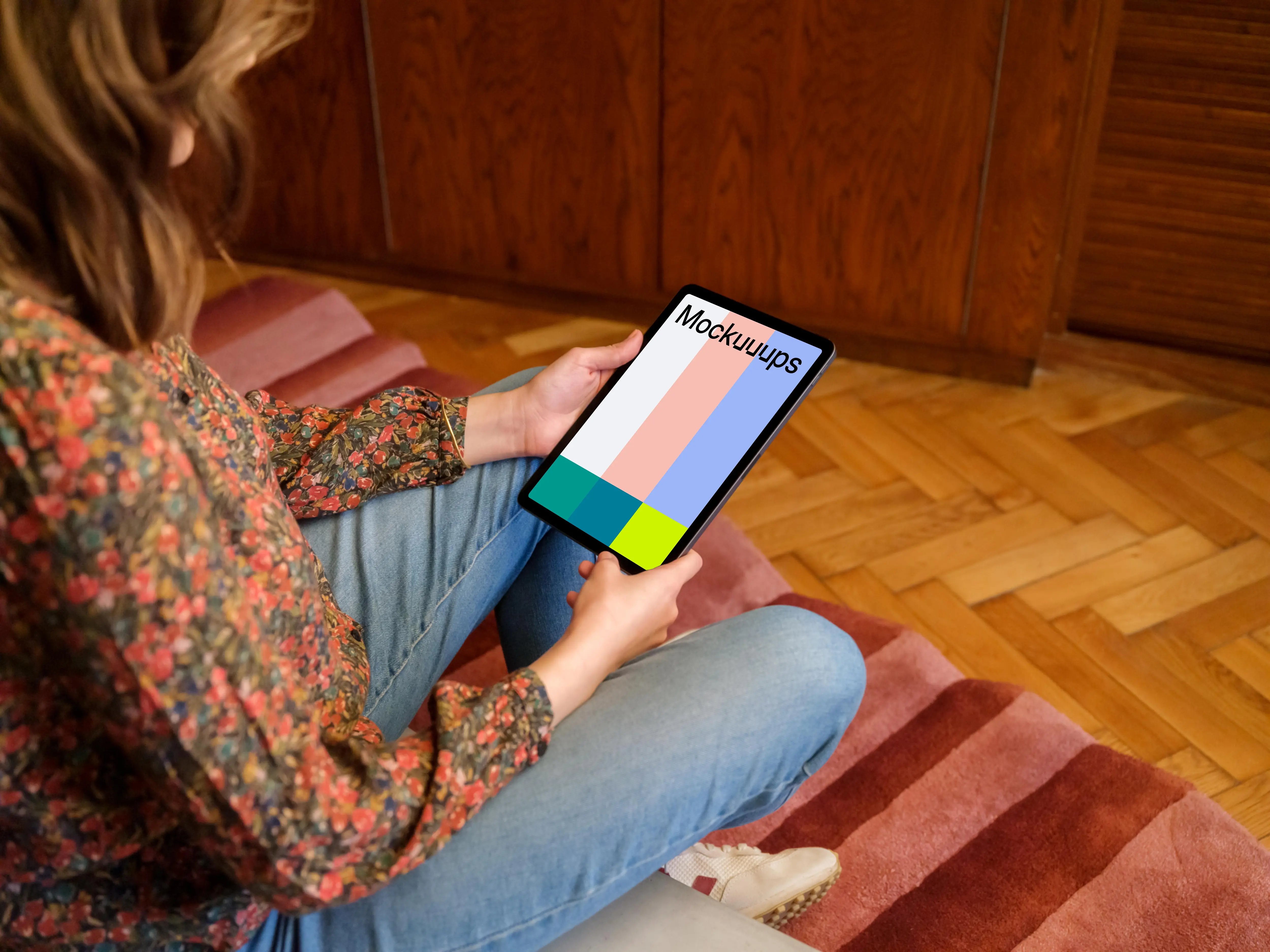 Female holding iPad mockup against a wooden background in the lounge