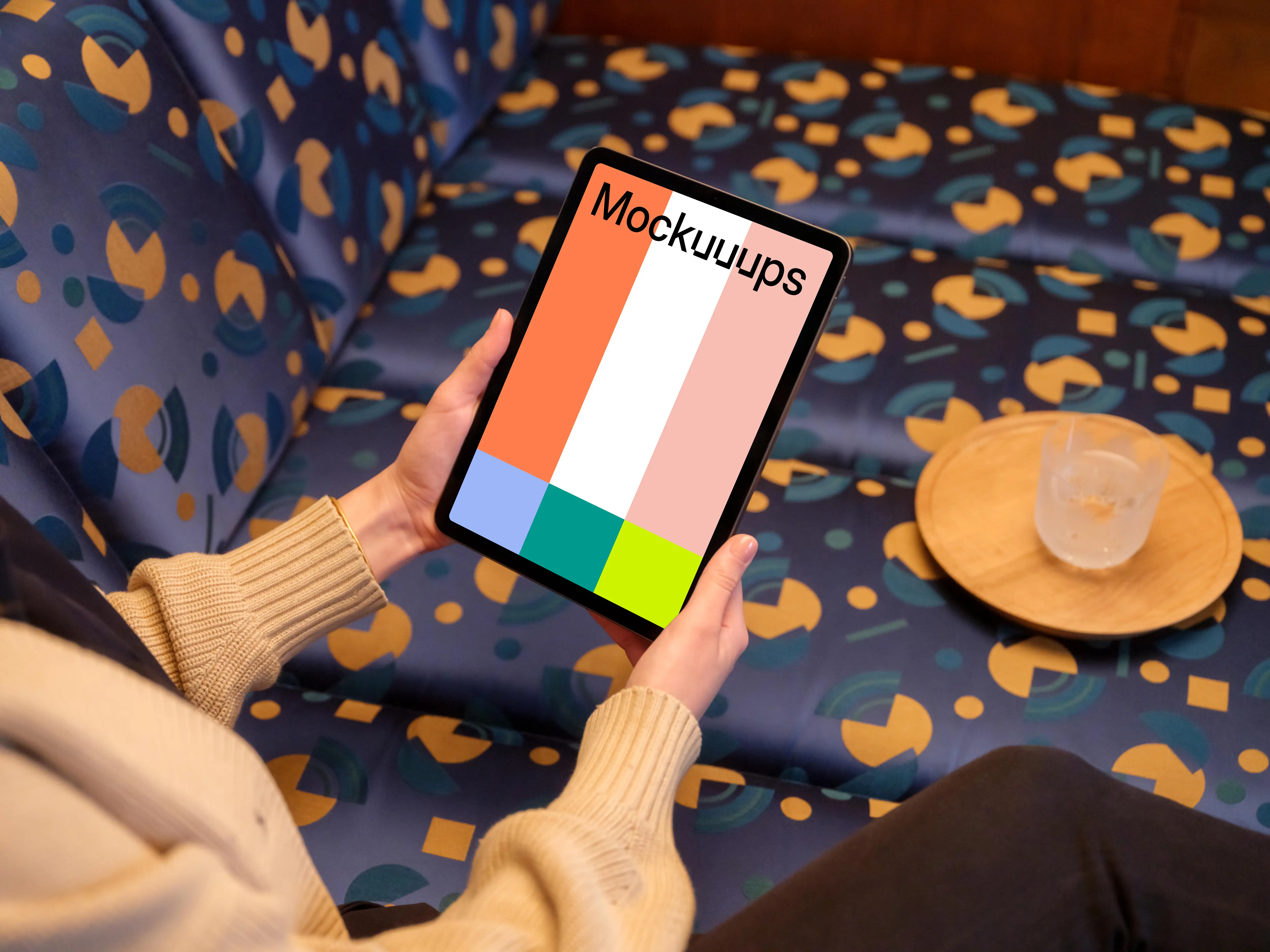 Female holding iPad mockup in colorful lounge setting