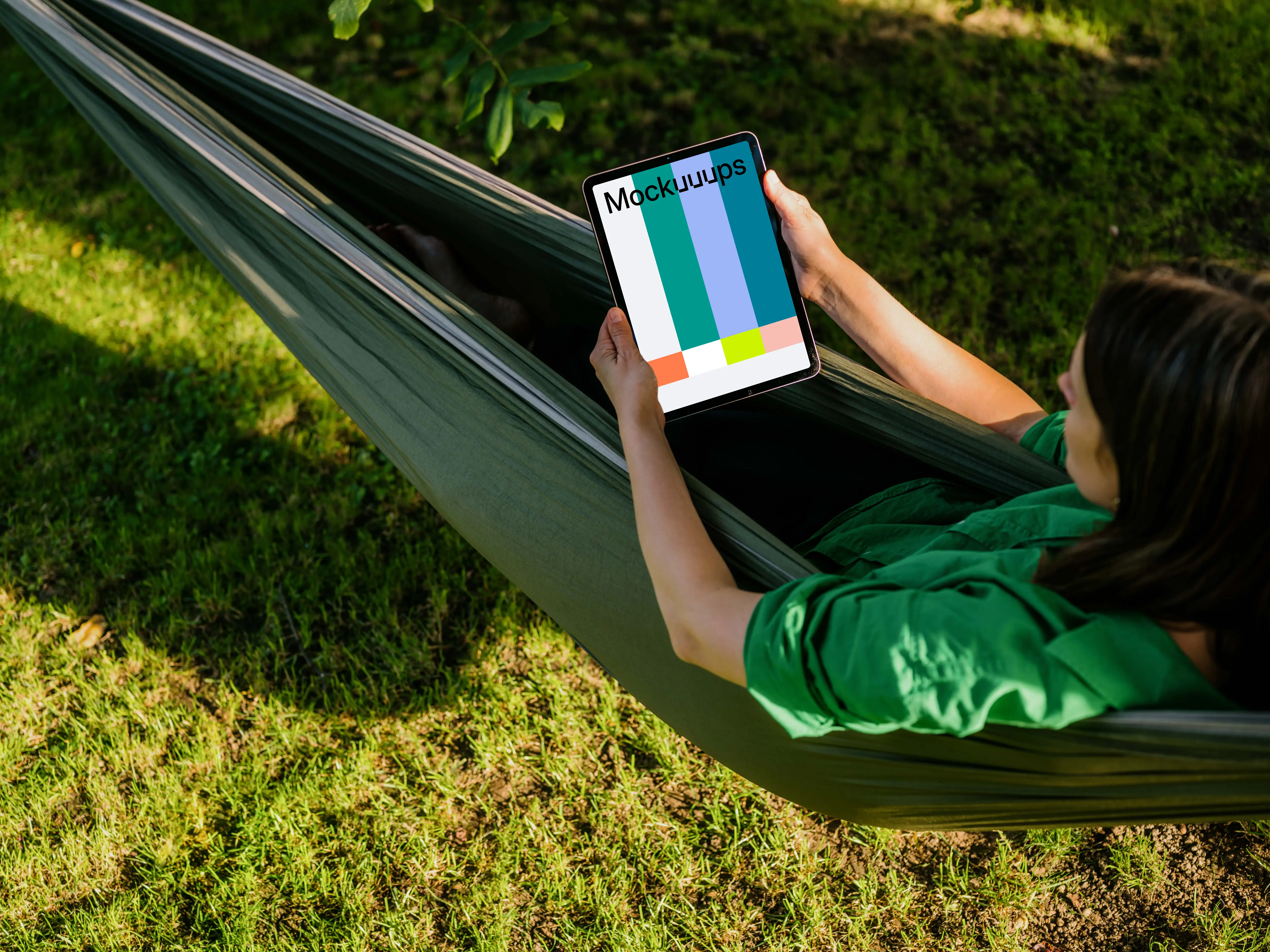 Female laying in hammock while holding a tablet