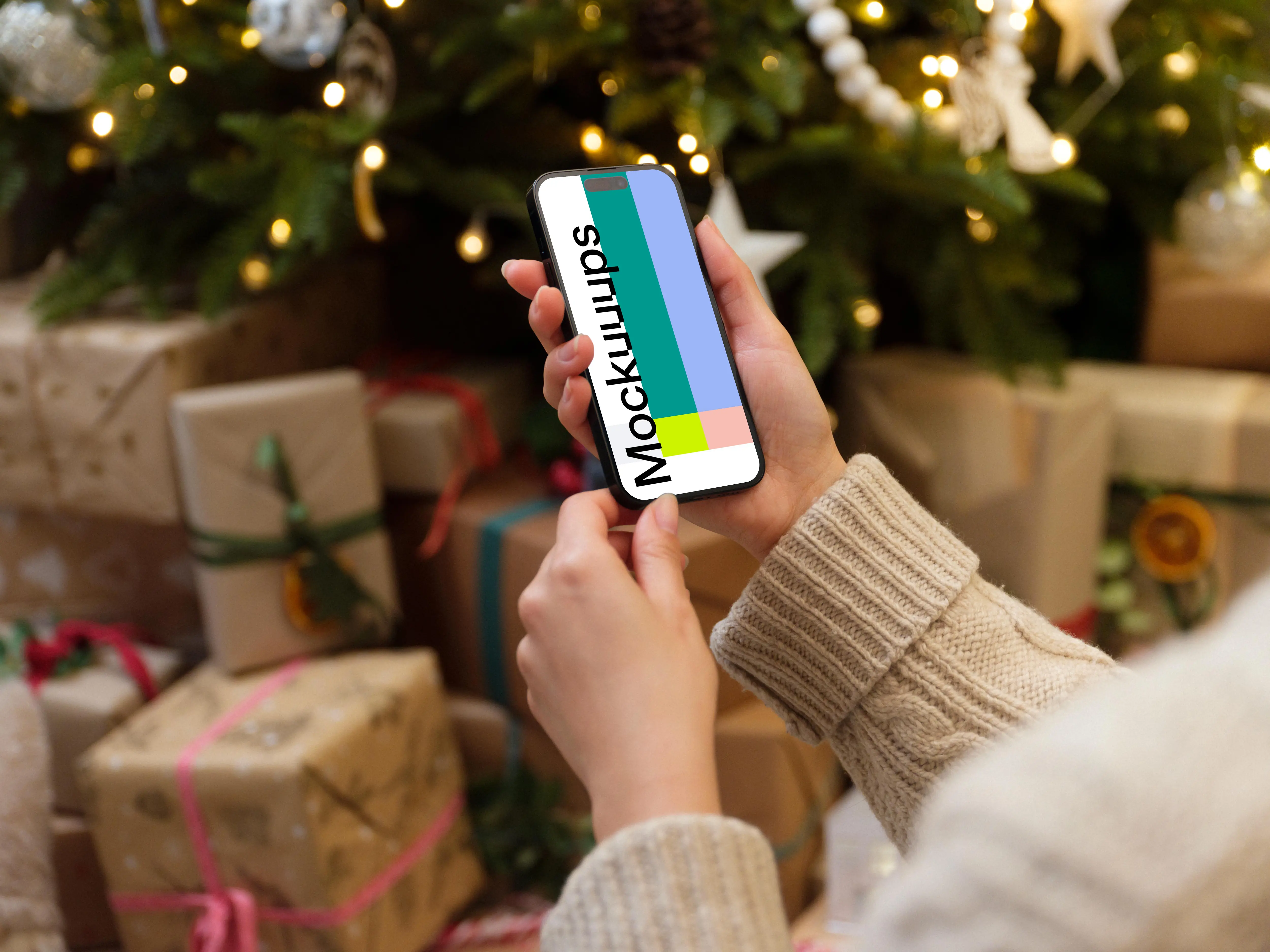 Hand holding a phone mockup next to the Christmas tree with gifts