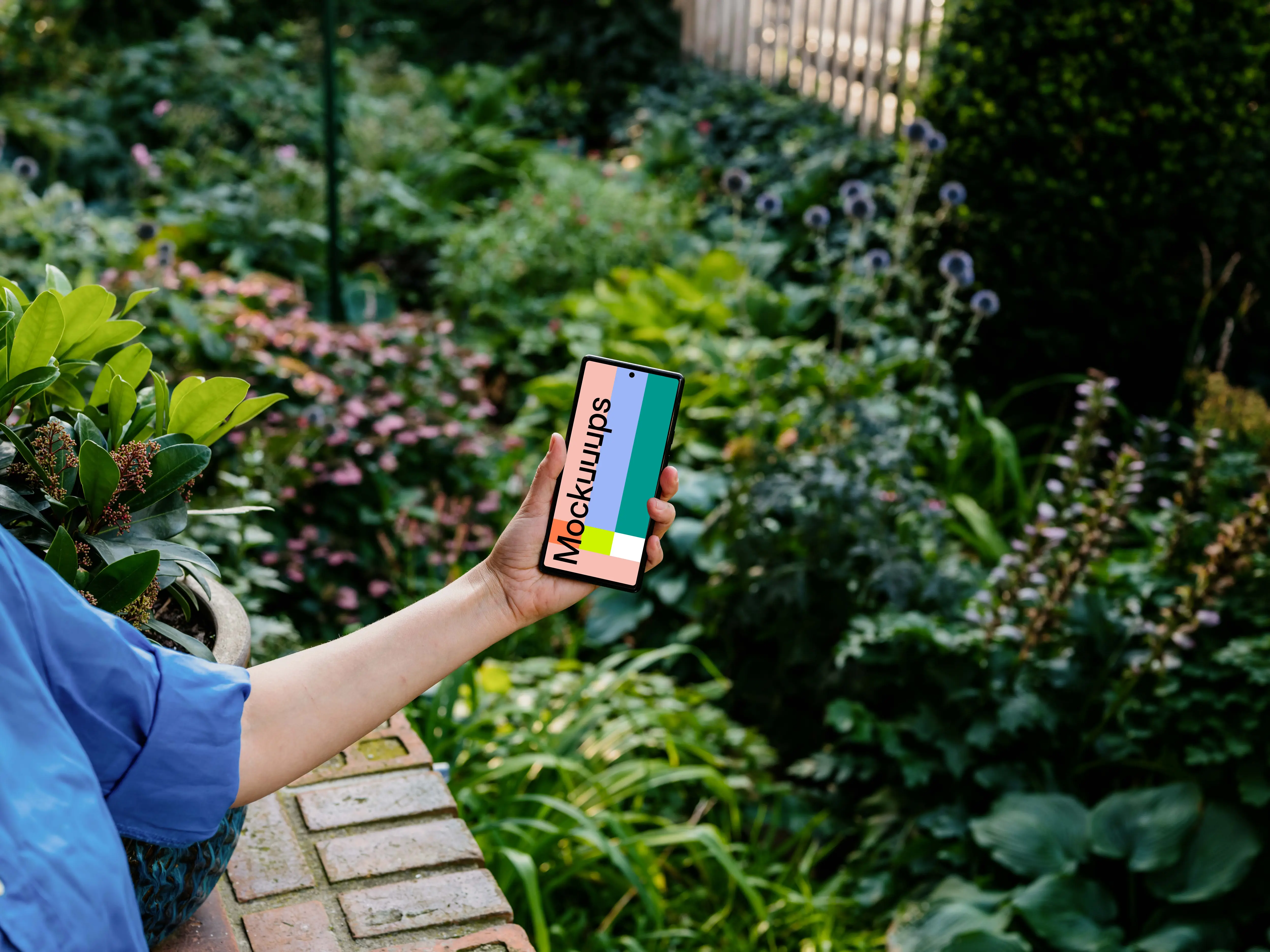 Hand holding a phone mockup with background full of plants