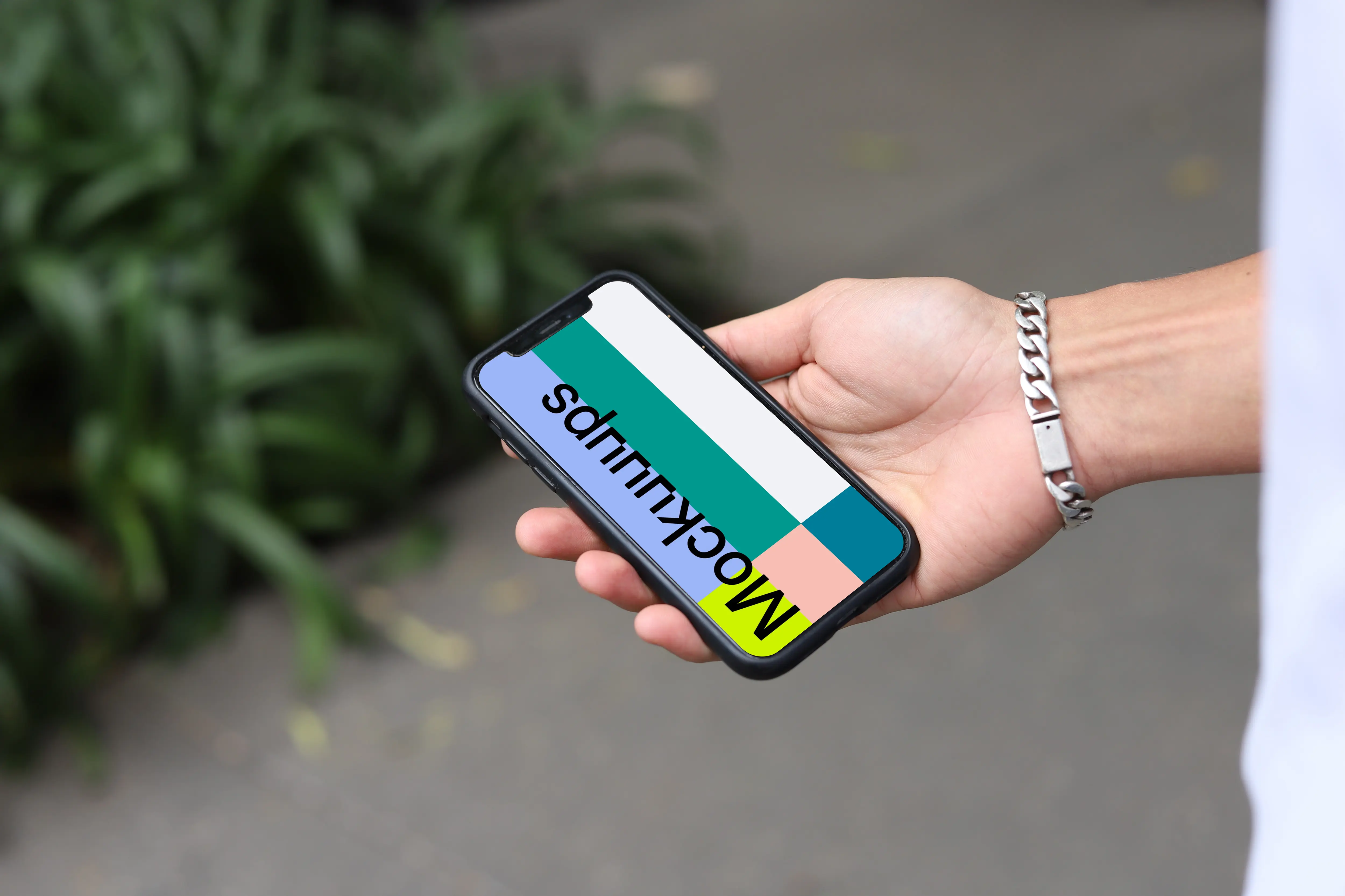 Hand with a bracelet holding an iPhone mockup