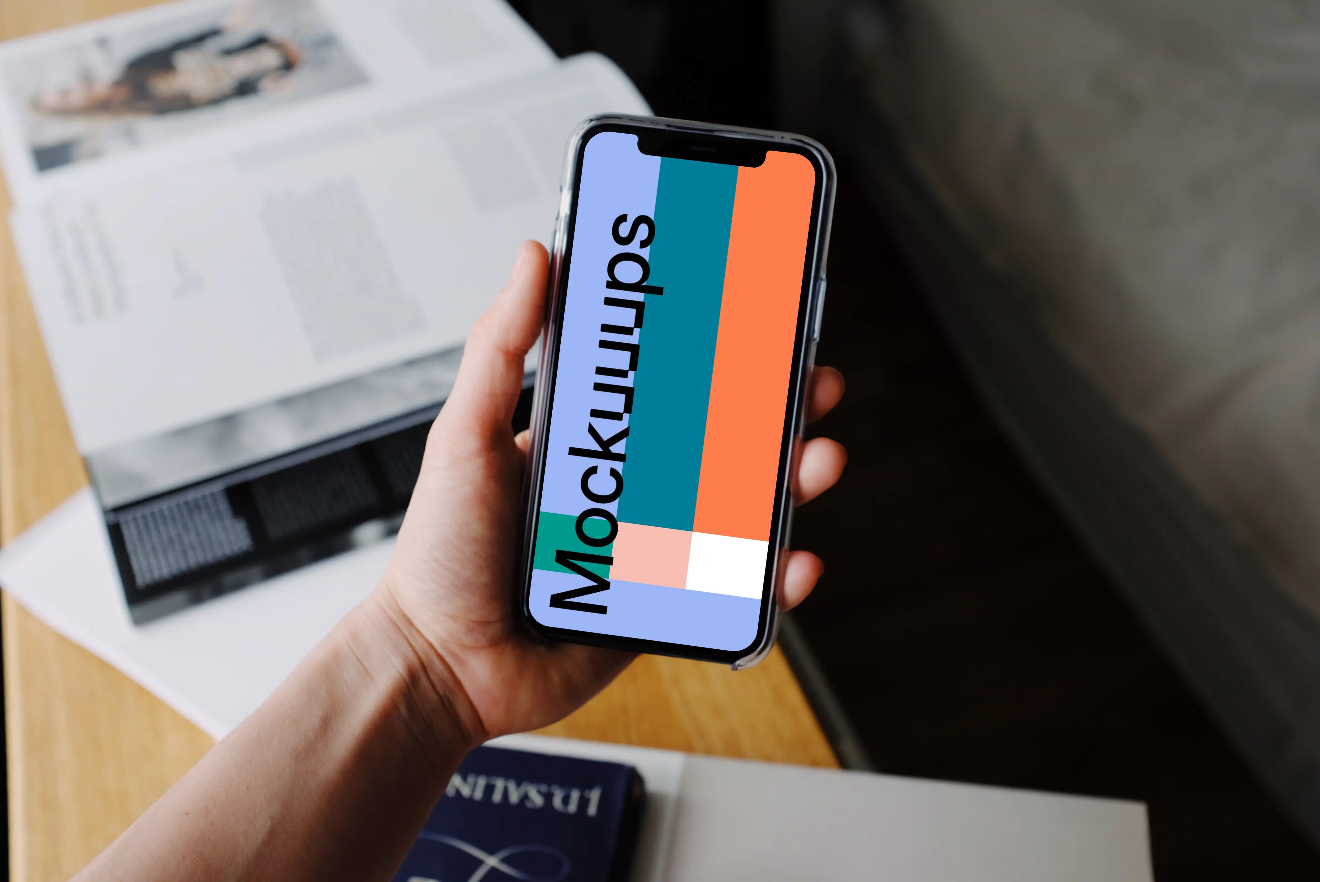 iPhone 12 Pro mockup held by user over textbooks