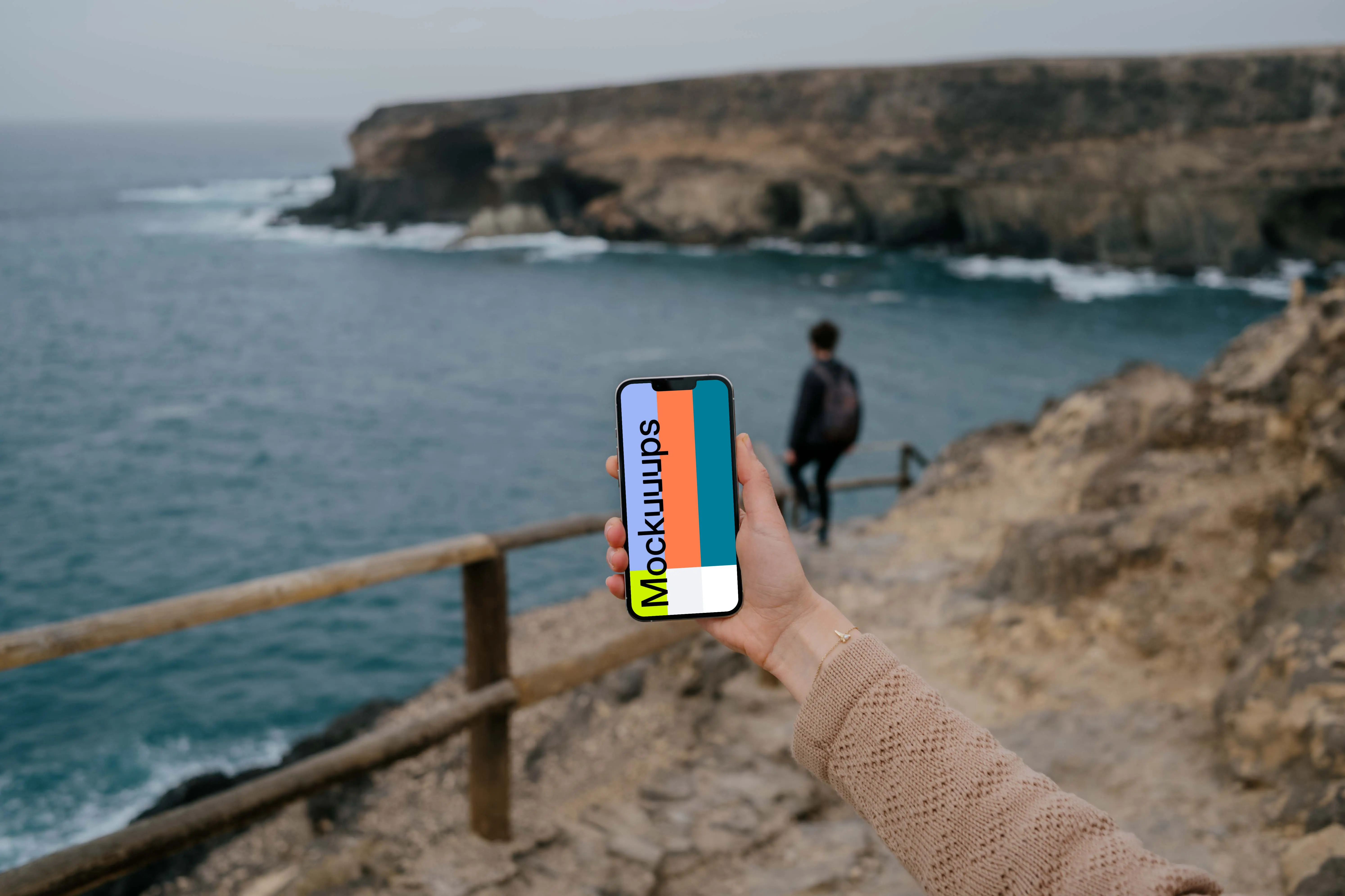 iPhone 13 Pro mockup held by a user at a coastline