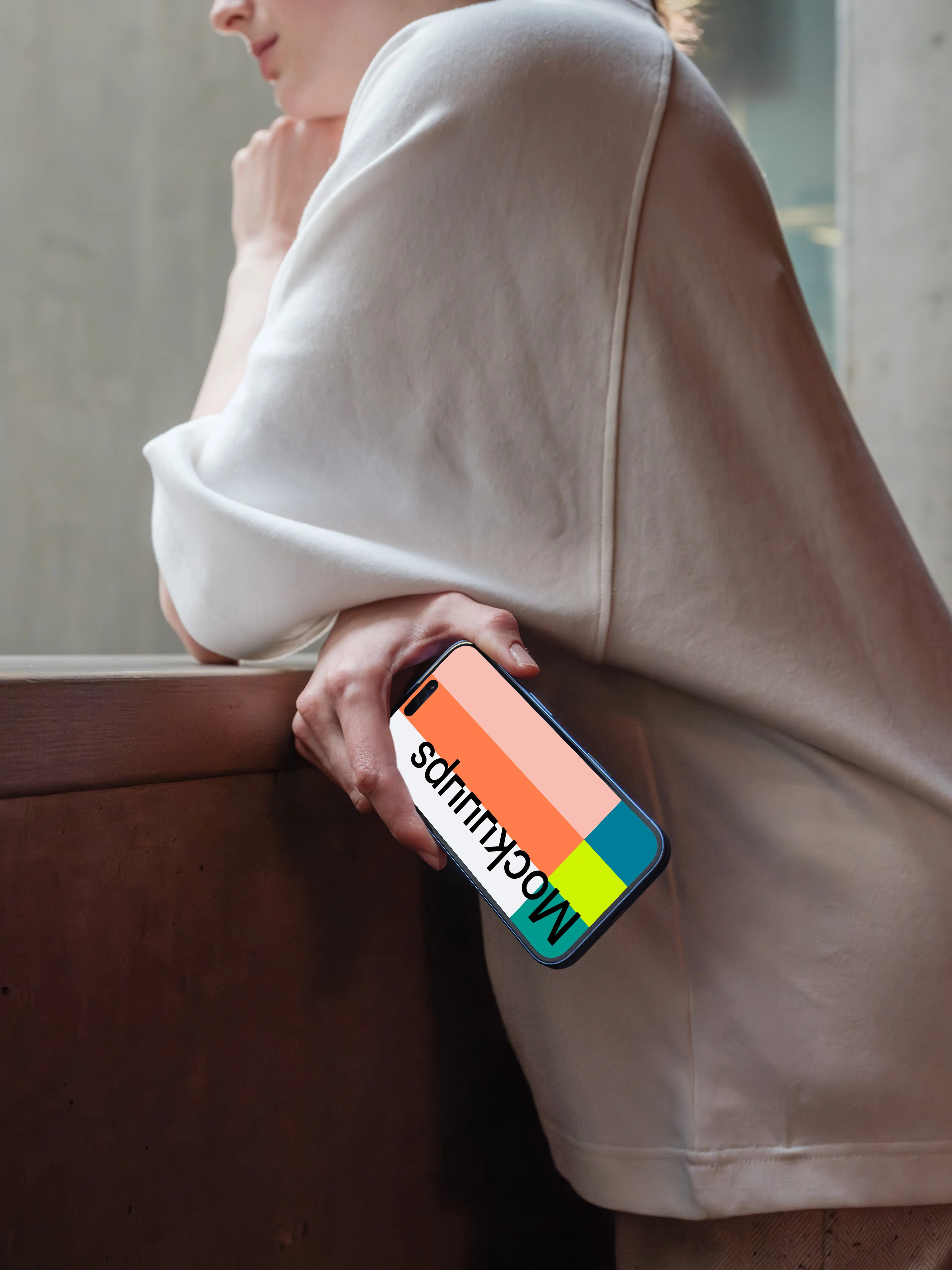 iPhone 16 mockup held by a person near a concrete surface