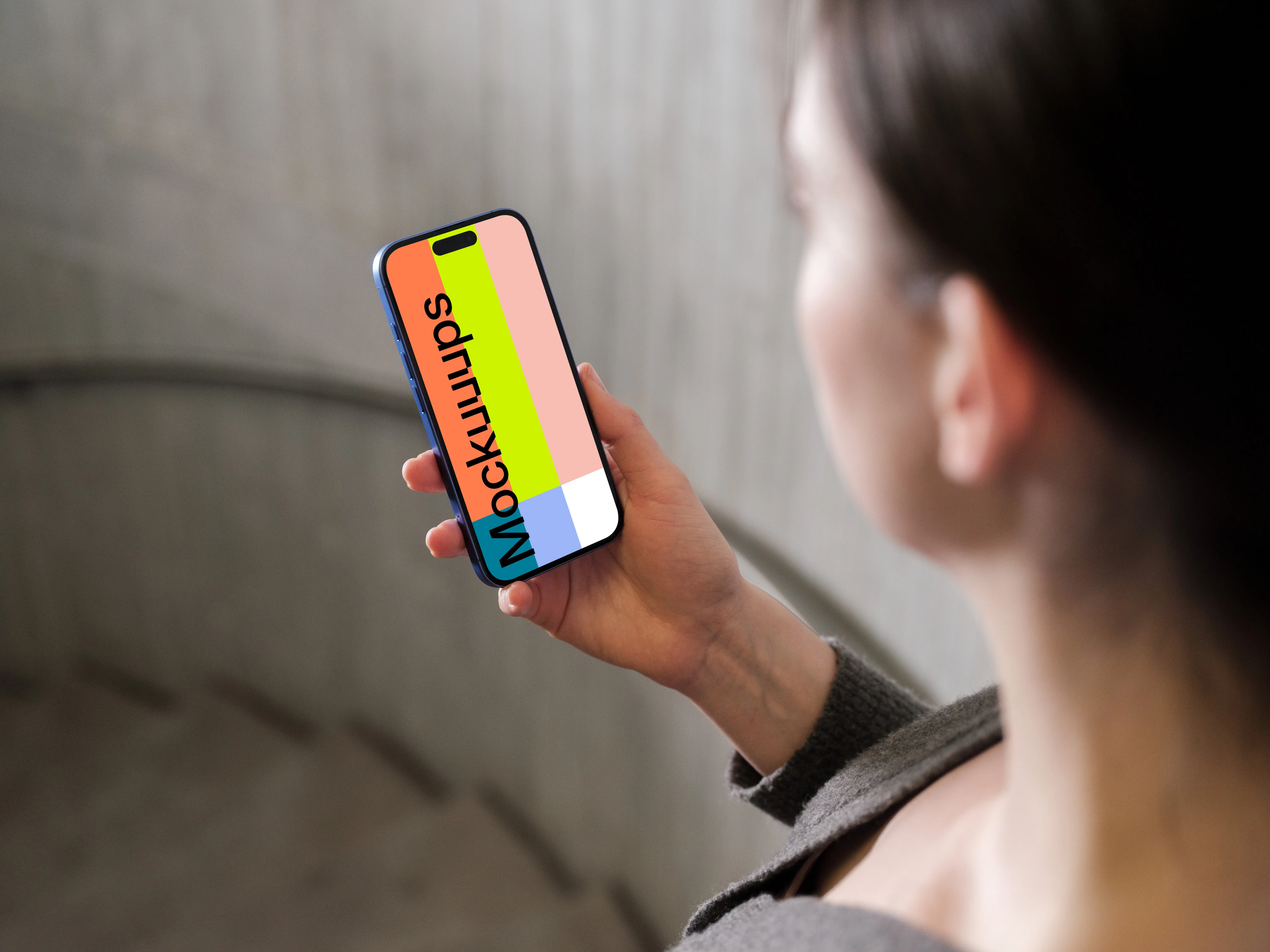 iPhone 16 mockup held in a woman's hand against concrete background