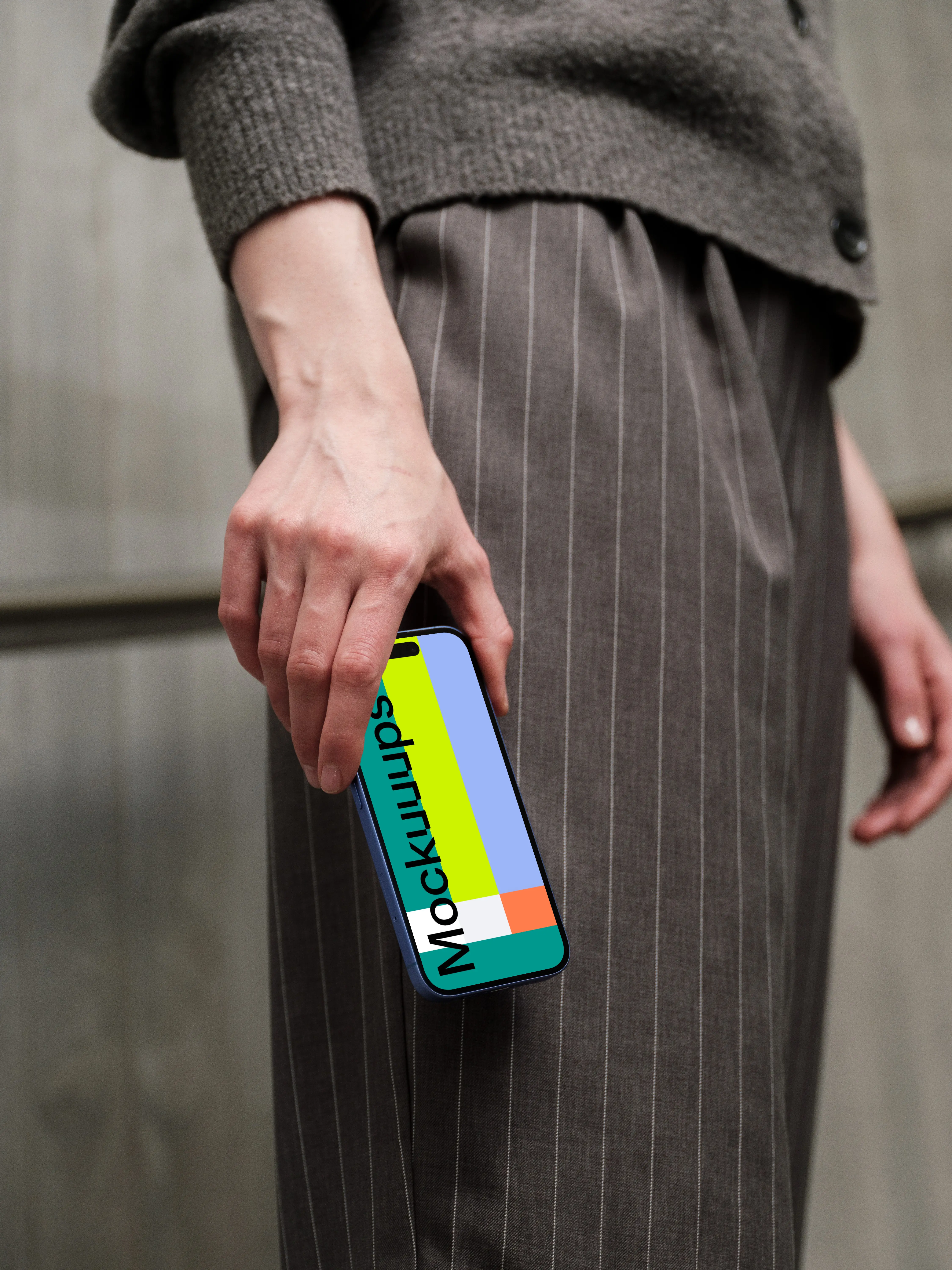 iPhone 16 mockup in hand with pinstripe pants