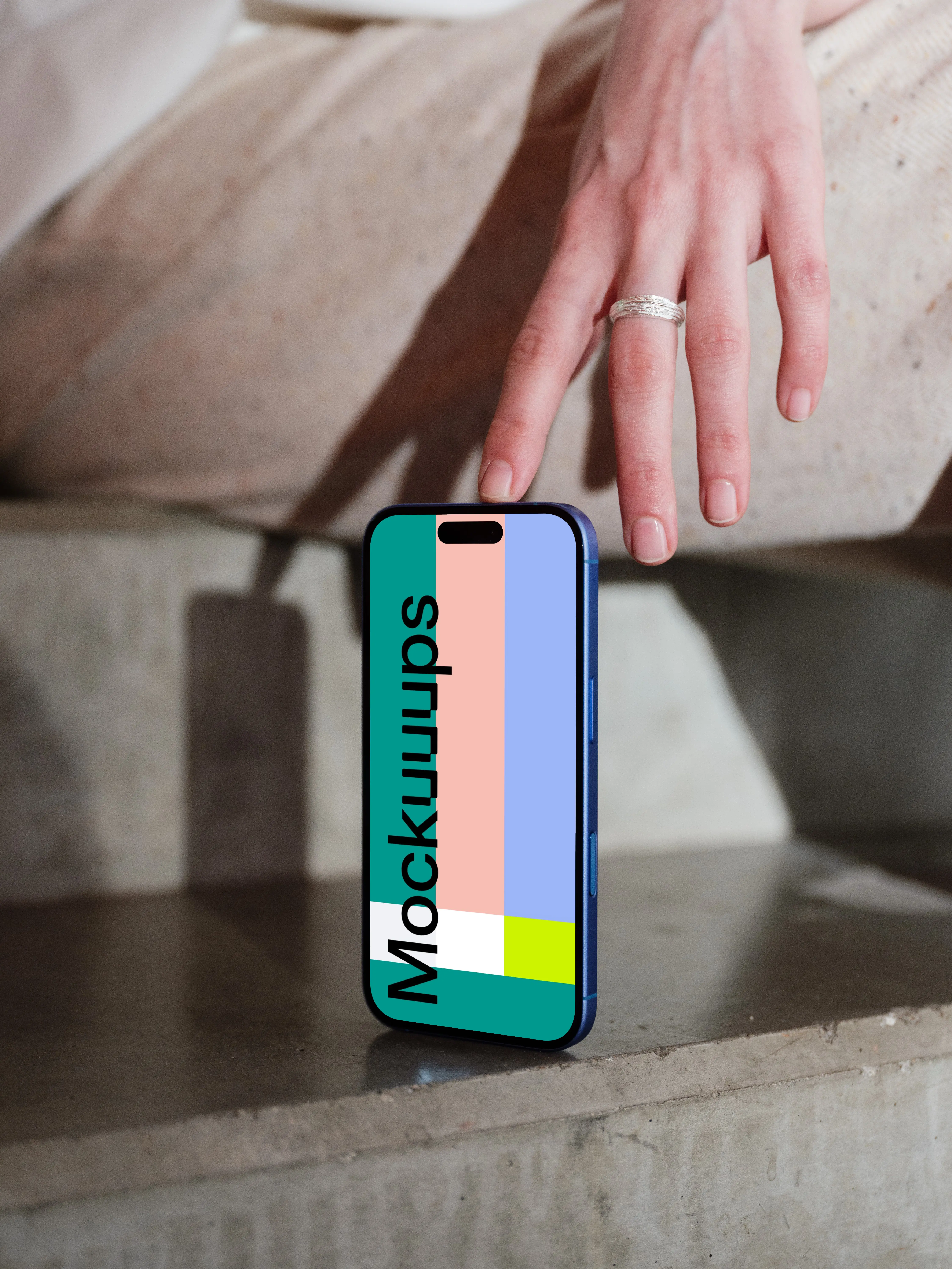 iPhone 16 mockup on a concrete surface with hand detail