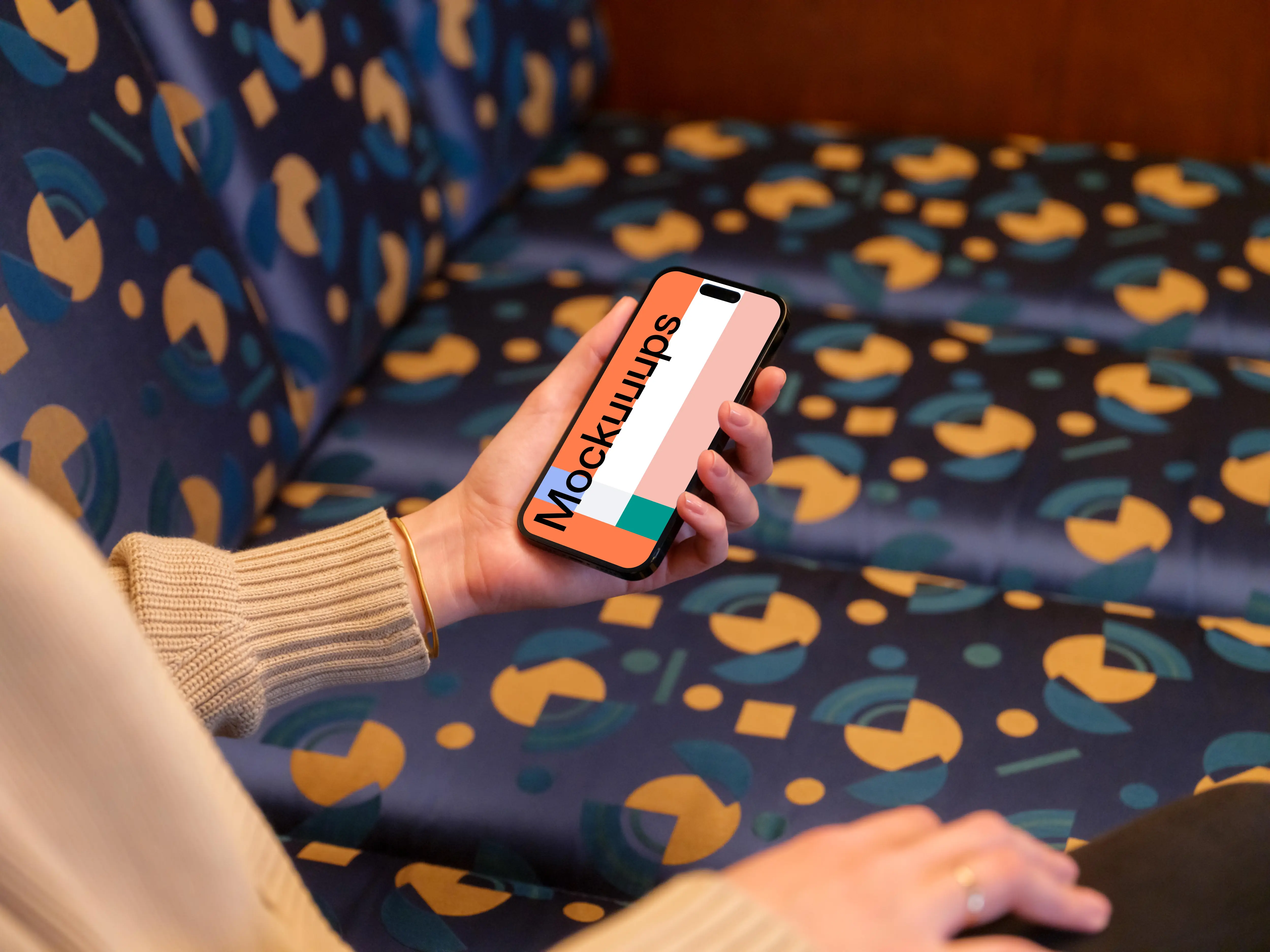 iPhone mockup held by woman’s hand in the lounge 