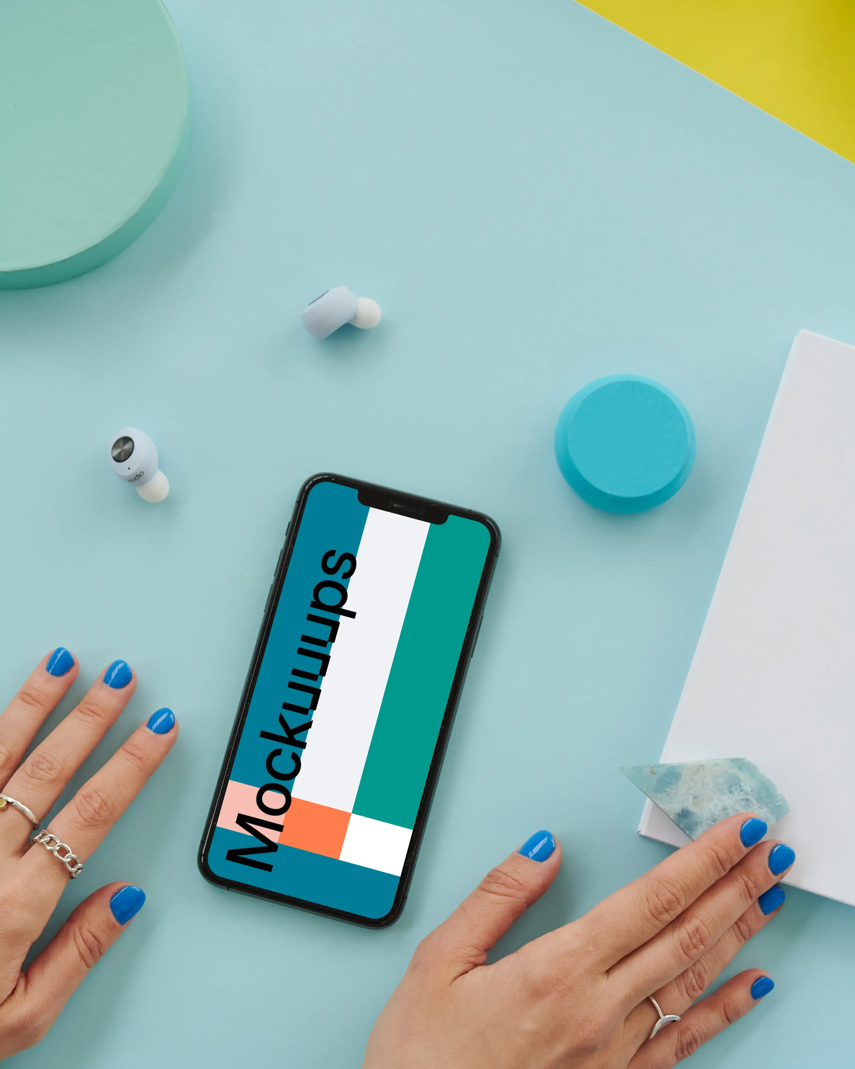  iPhone mockup on a blue table beside a pair of earbuds