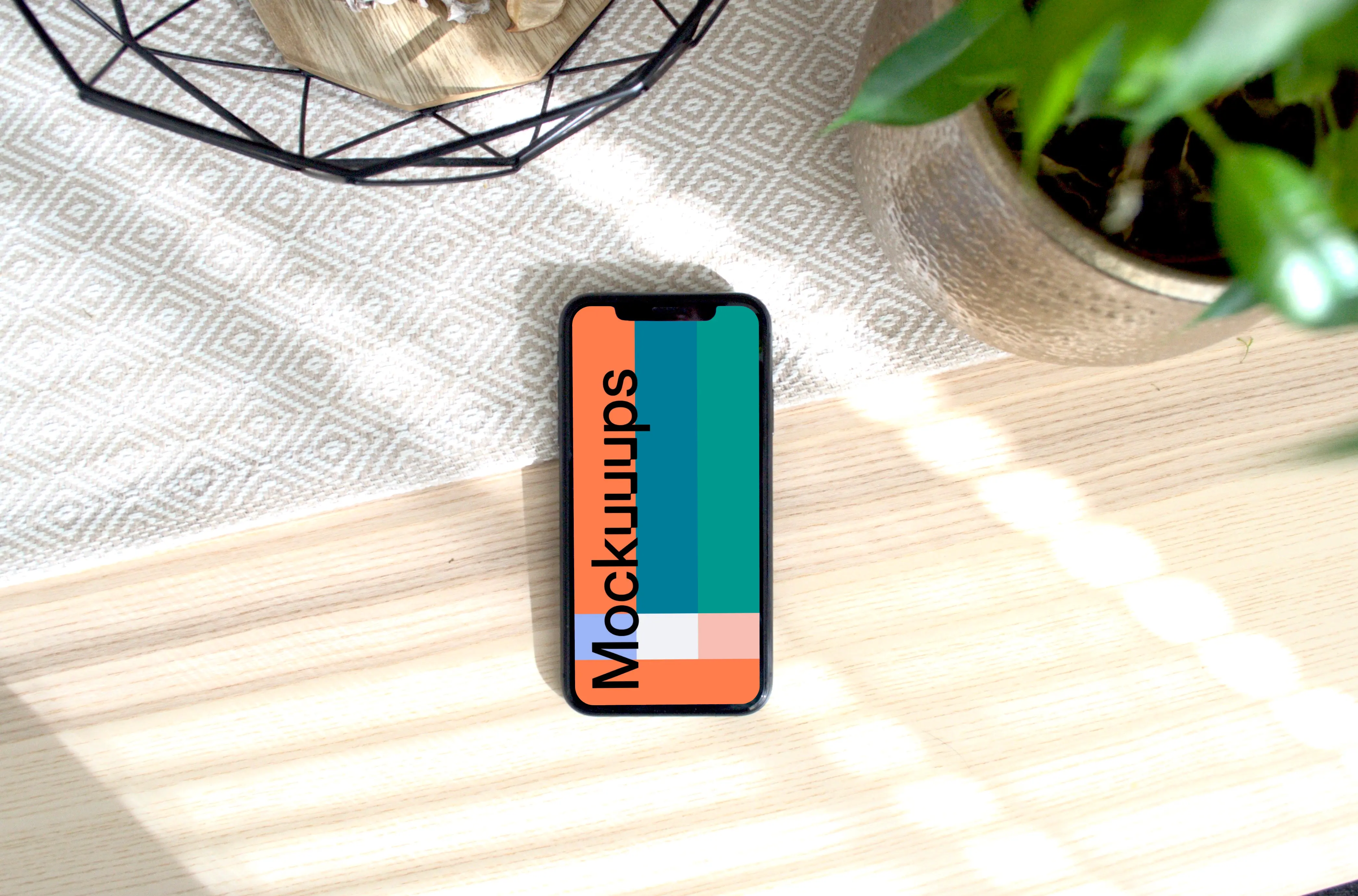 iPhone mockup on a table with a flower pot at the side.