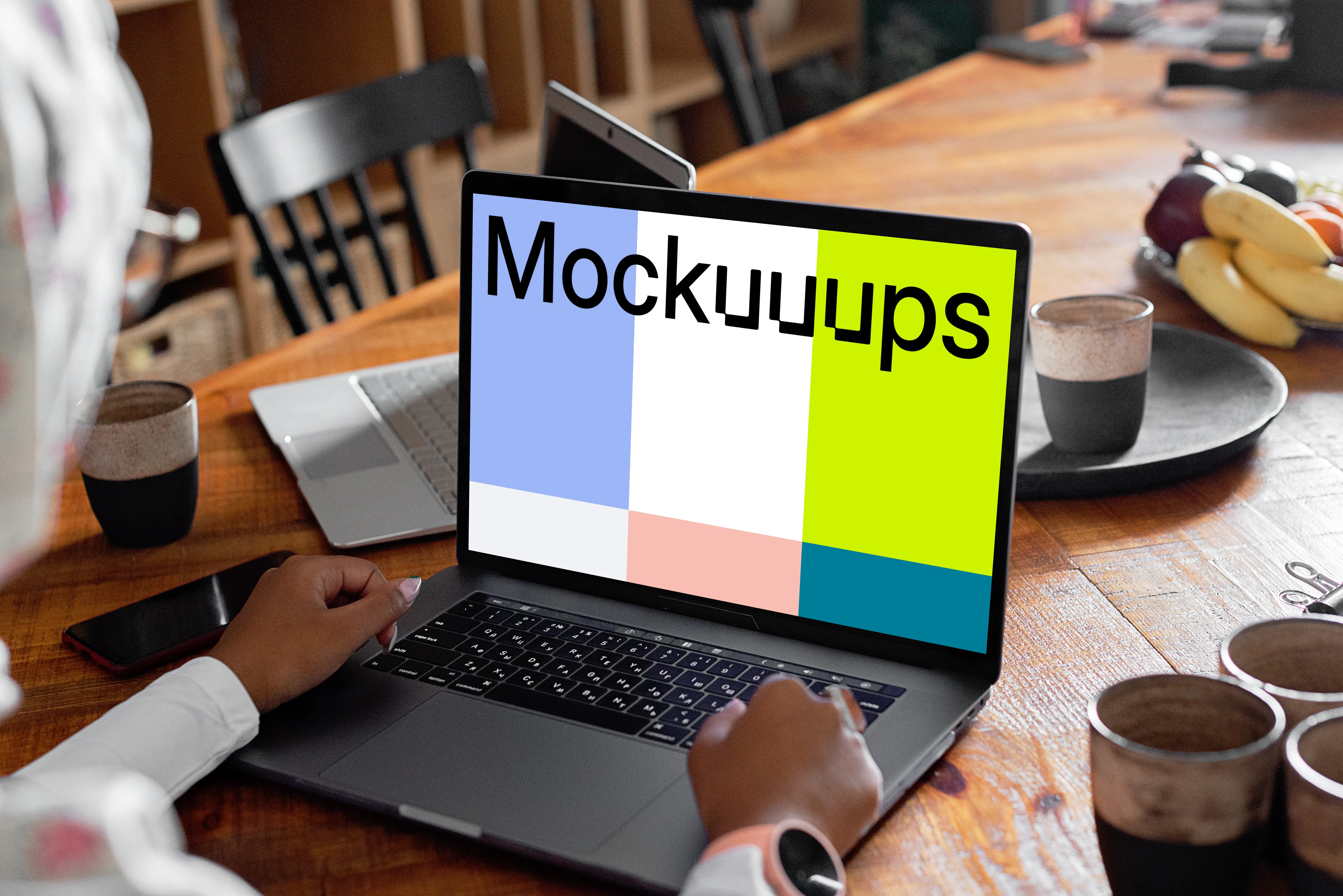 MacBook Air mockup in use by a lady with coffee mugs at the side 