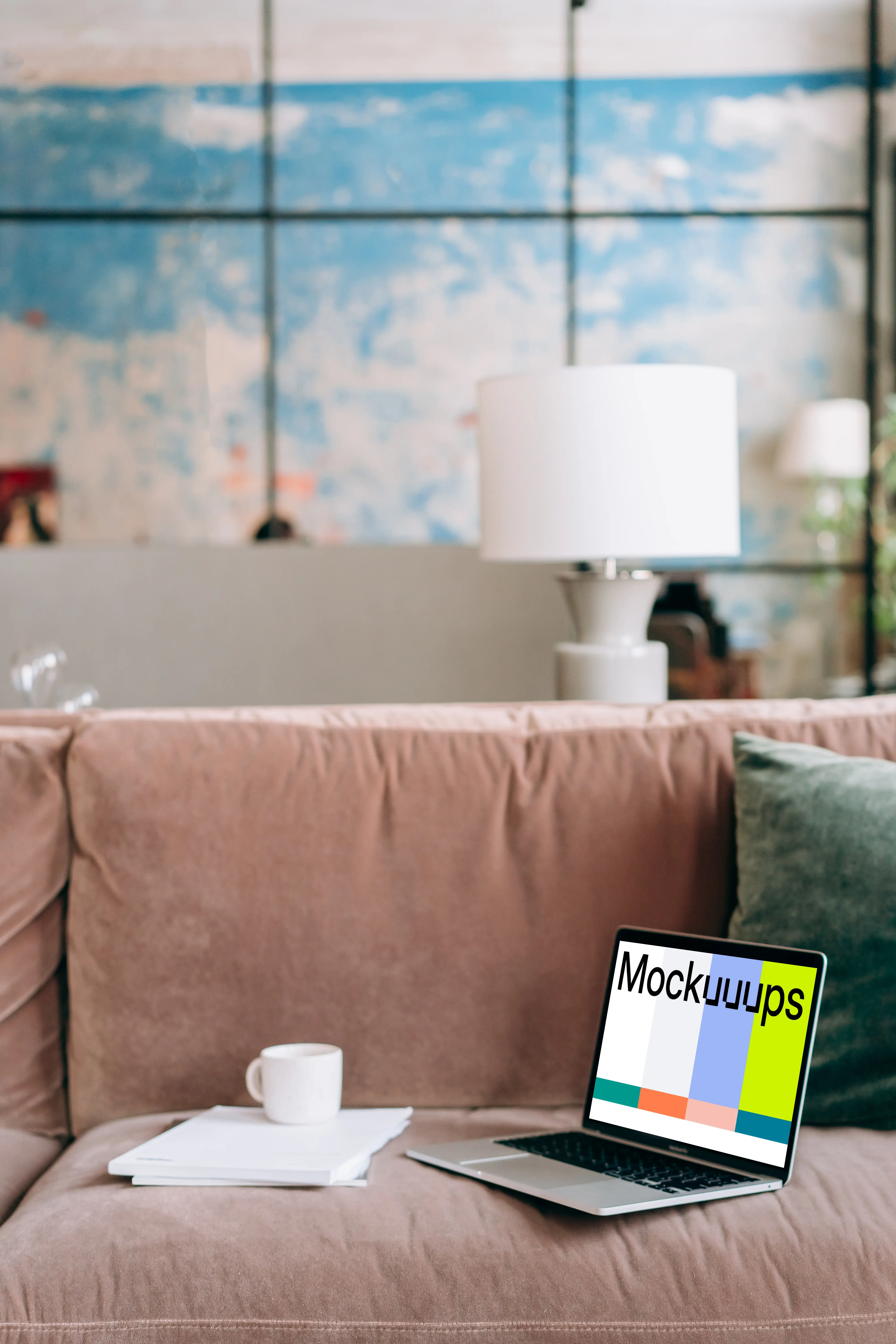 MacBook Pro mockup on a red sofa beside a couple of notepads