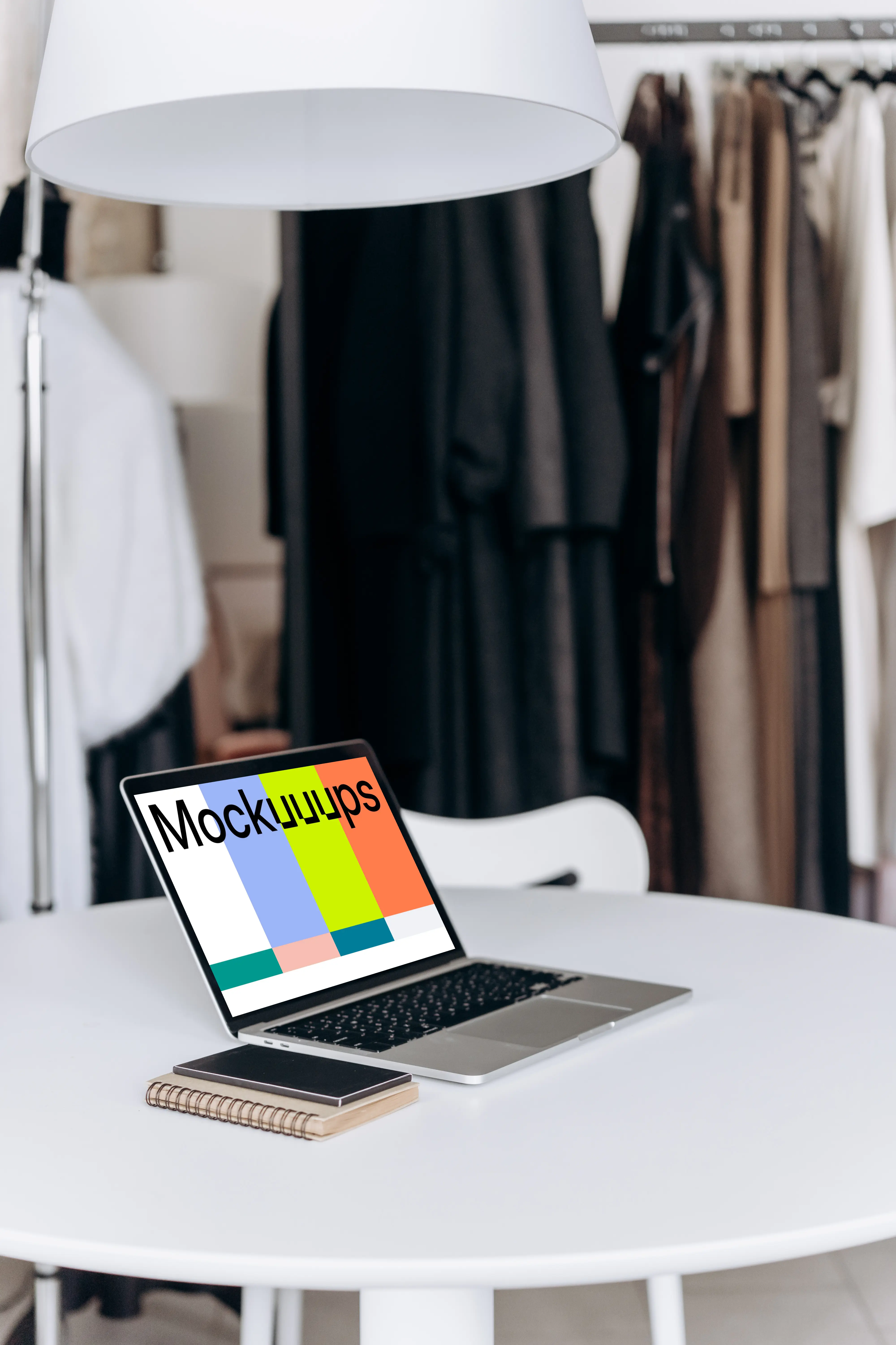 MacBook Pro mockup on a work table beside phone and notepad