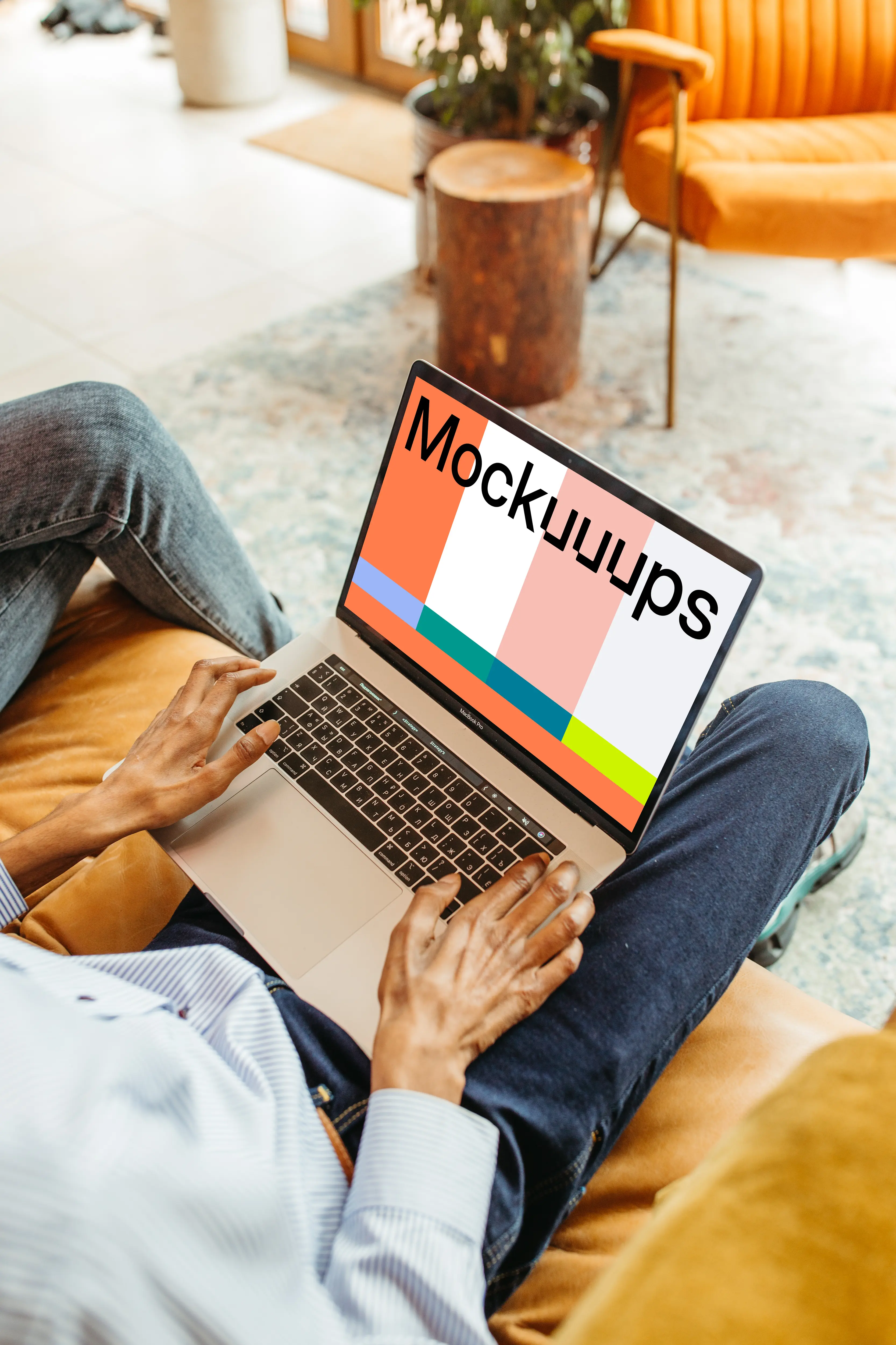 Male user sitting on a chair and using a MacBook Pro mockup