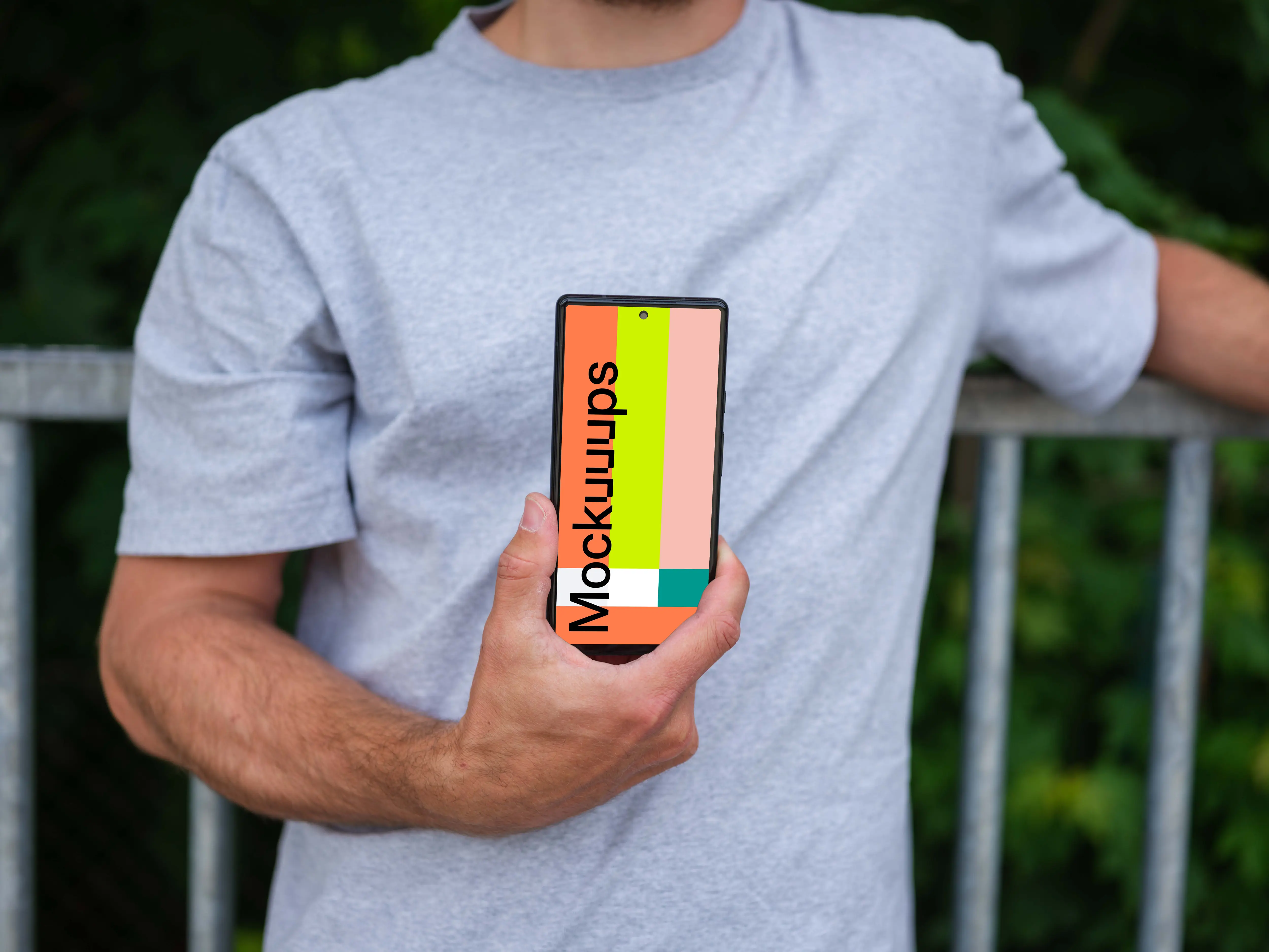 Man holding a phone mockup in front of a fence