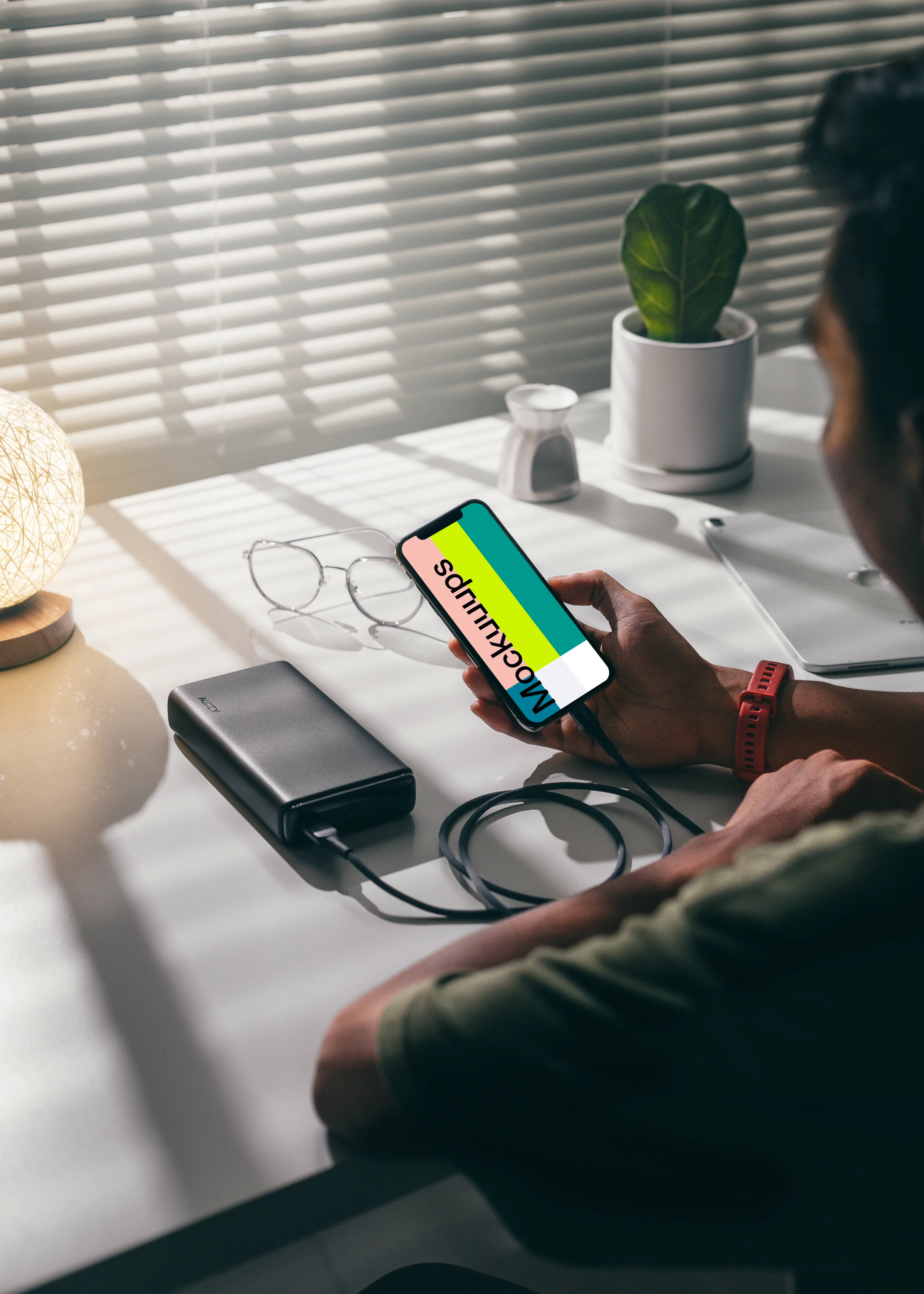 Man holding an iPhone 12 mockup plugged into a power bank