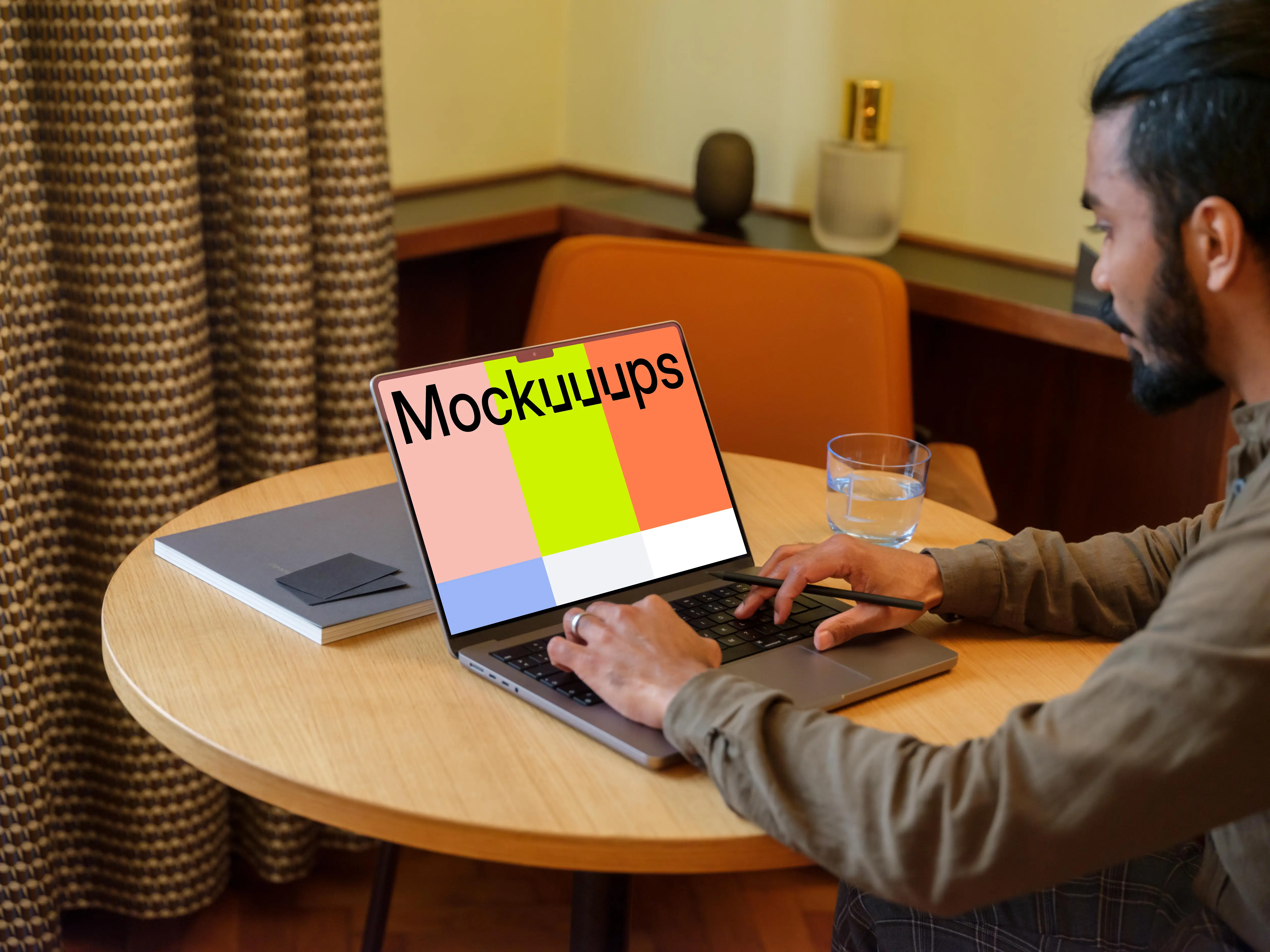 Man typing on a MacBook Pro mockup in a lounge