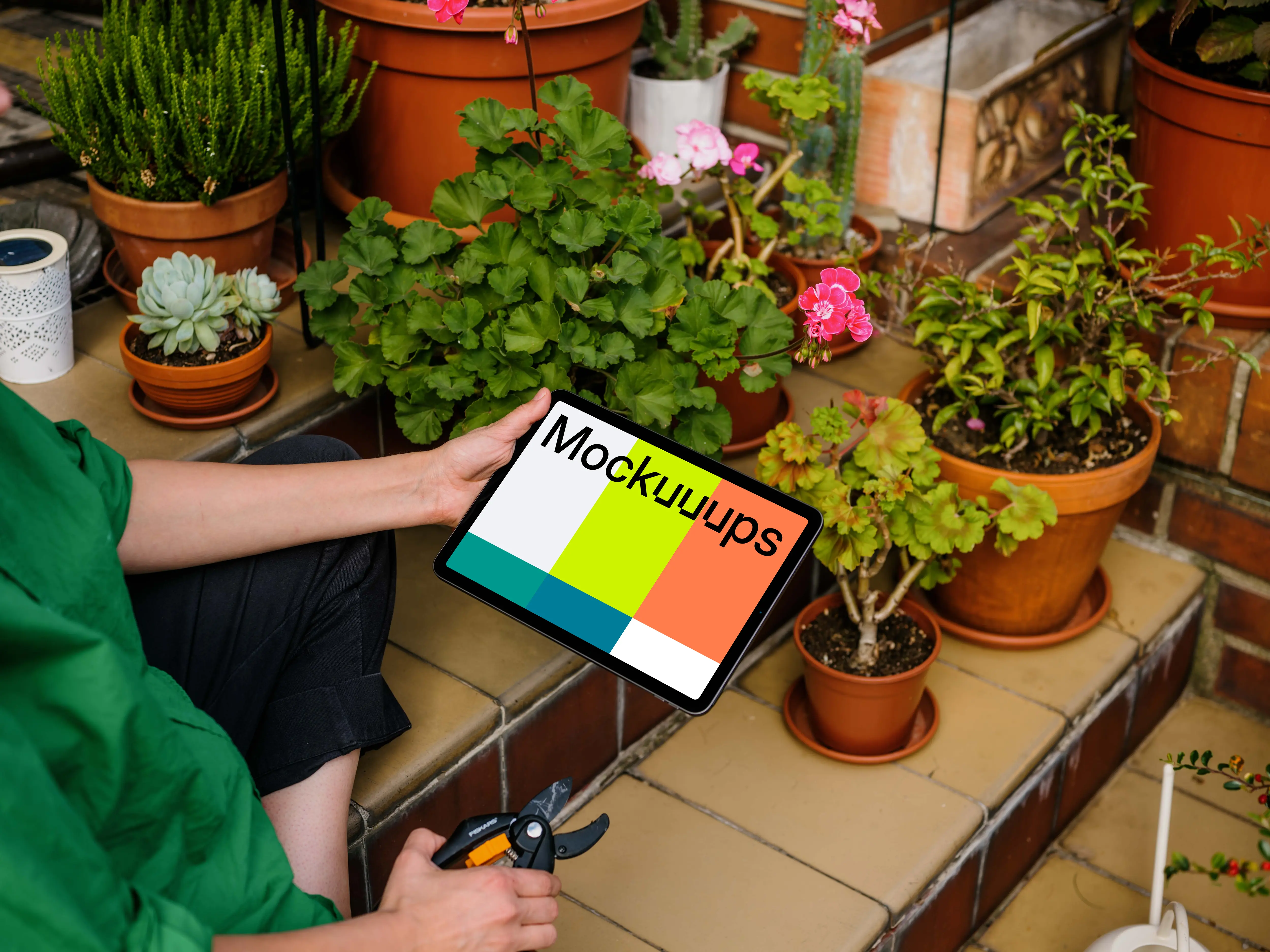 Woman holding an iPad Air mockup and taking care of flowers