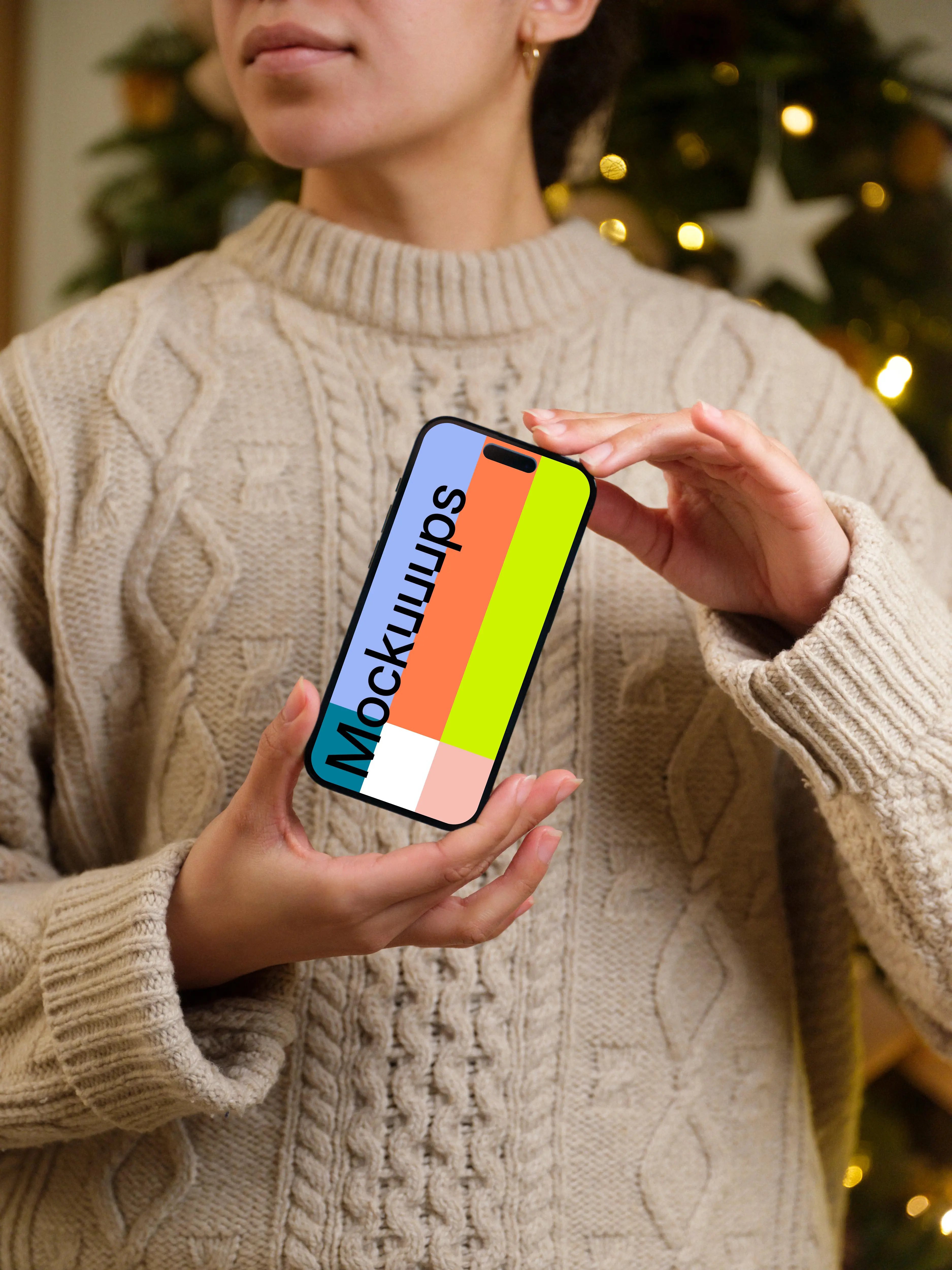 Woman holding an iPhone 14 Pro mockup next to the Christmas tree