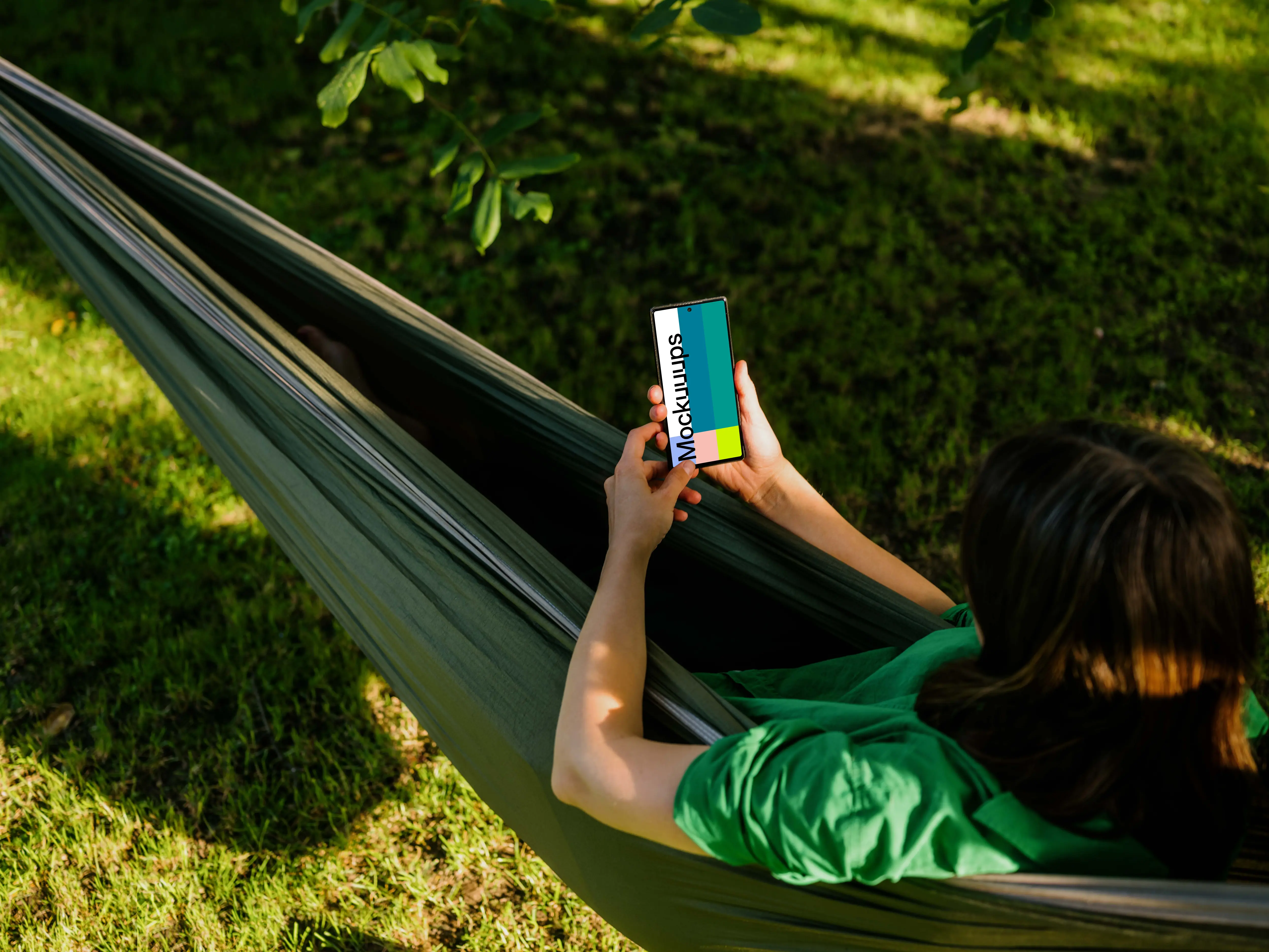 Woman laying in hammock holding a phone mockup
