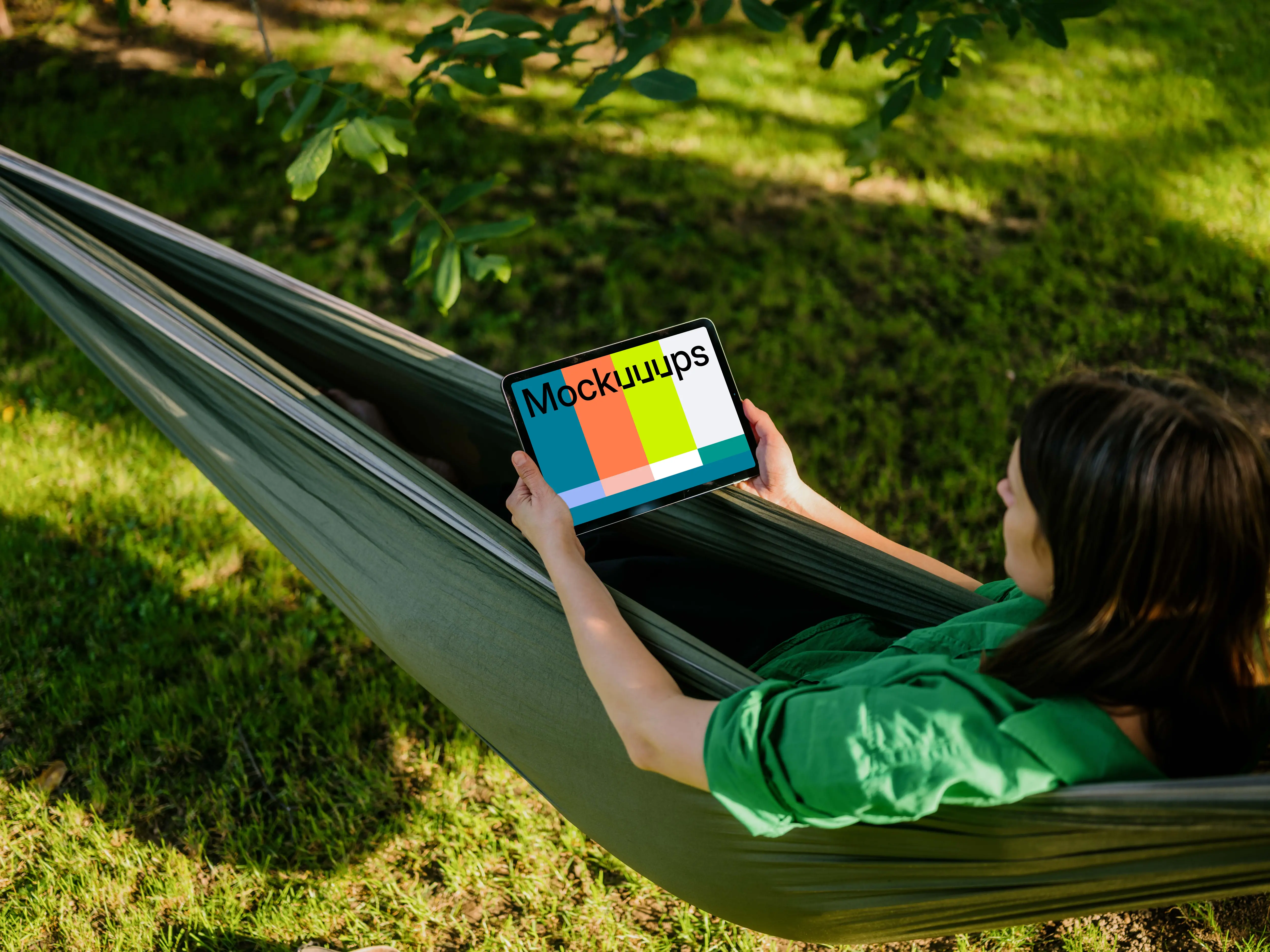 Woman laying in hammock while holding a tablet